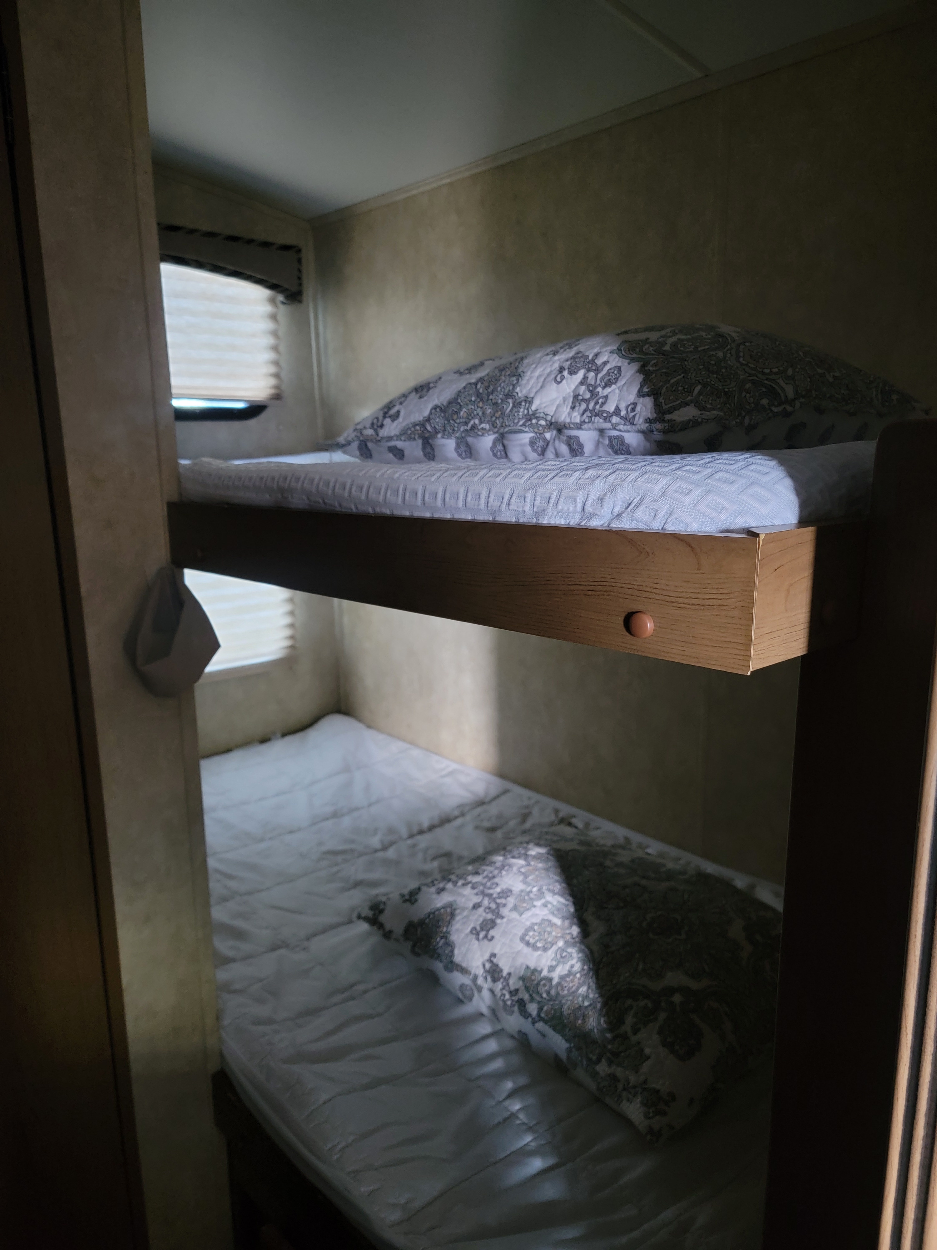 Cozy bunk beds in an RV rental, featuring a neatly made top and bottom bunk, perfect for compact sleeping quarters.. 5RXTD2221F1032421 Shadow Cruiser 2015