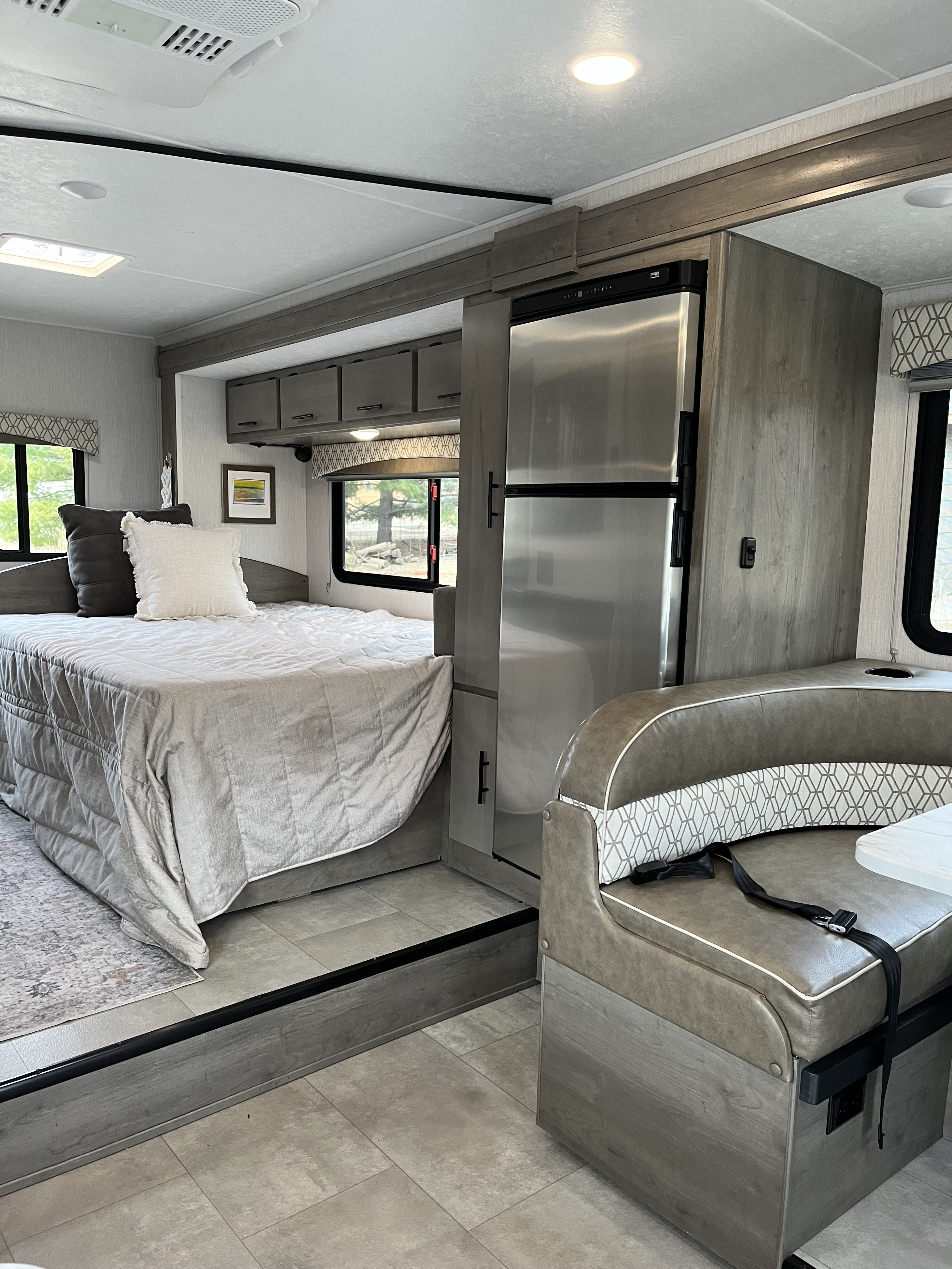 Cozy RV rental interior featuring a gray-toned bedroom, modern kitchen, and comfortable dinette area.. Coachmen Freelander 23FS 2021