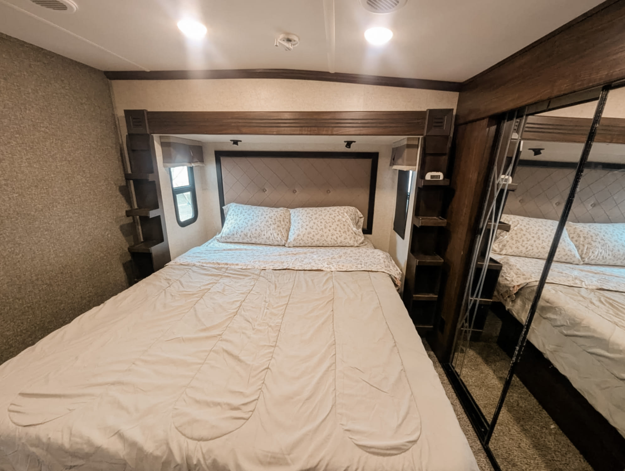 RV rental bedroom: large bed with light bedding, built-in storage, and mirrored closet doors.. Heartland RVs Gateway 2016