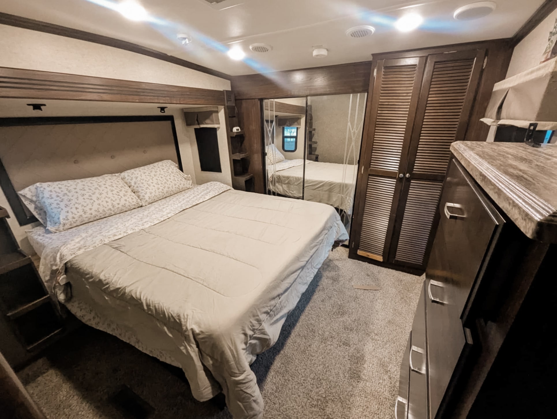 Spacious RV rental bedroom with a comfy bed, mirrored closet, and dresser, offering a cozy retreat on wheels.. Heartland RVs Gateway 2016