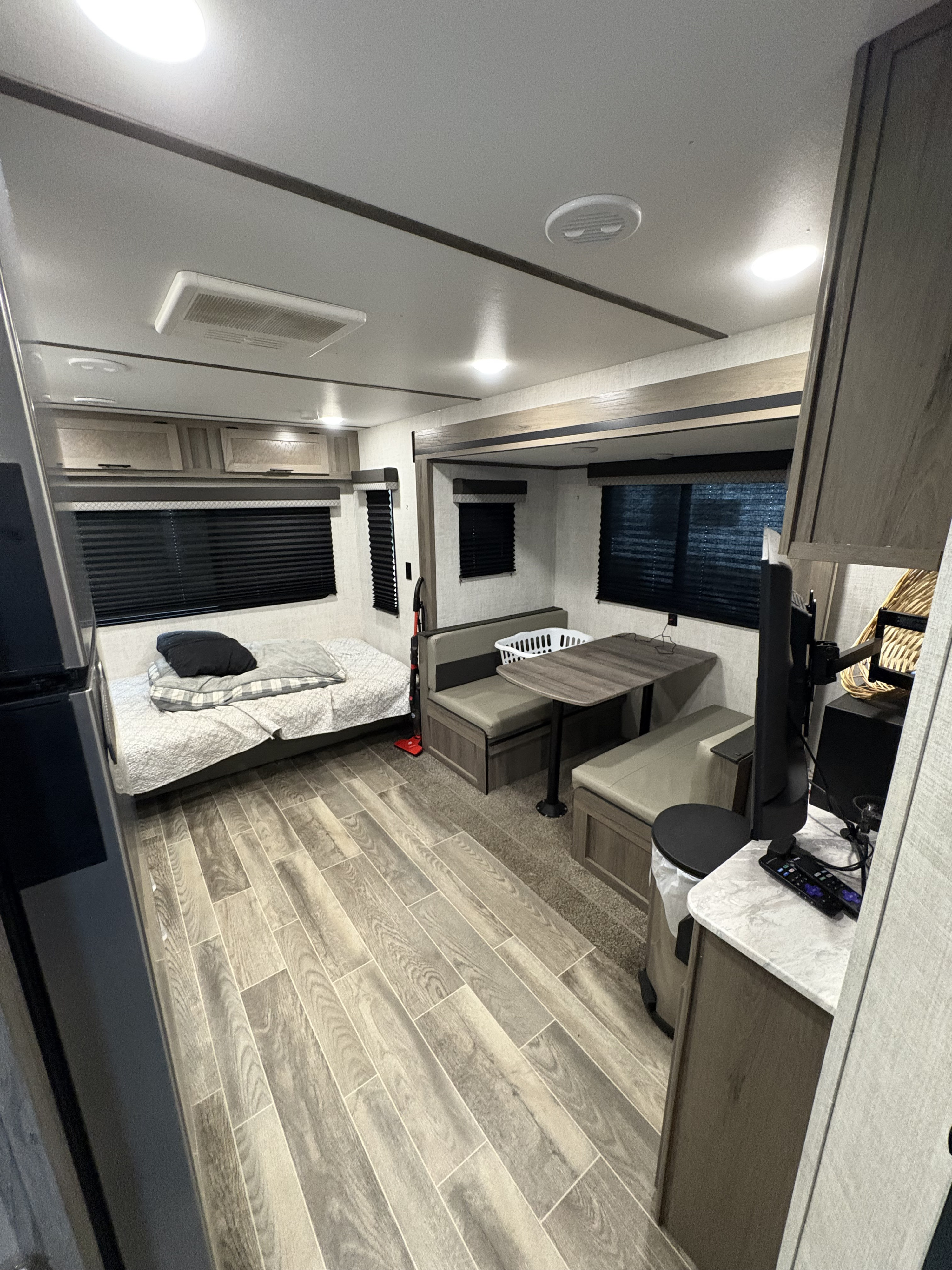 Inside an RV rental, showing a functional and cozy living space with a bed, dinette, and modern wood-look flooring.. Gulf Stream Ameri-Lite 2022
