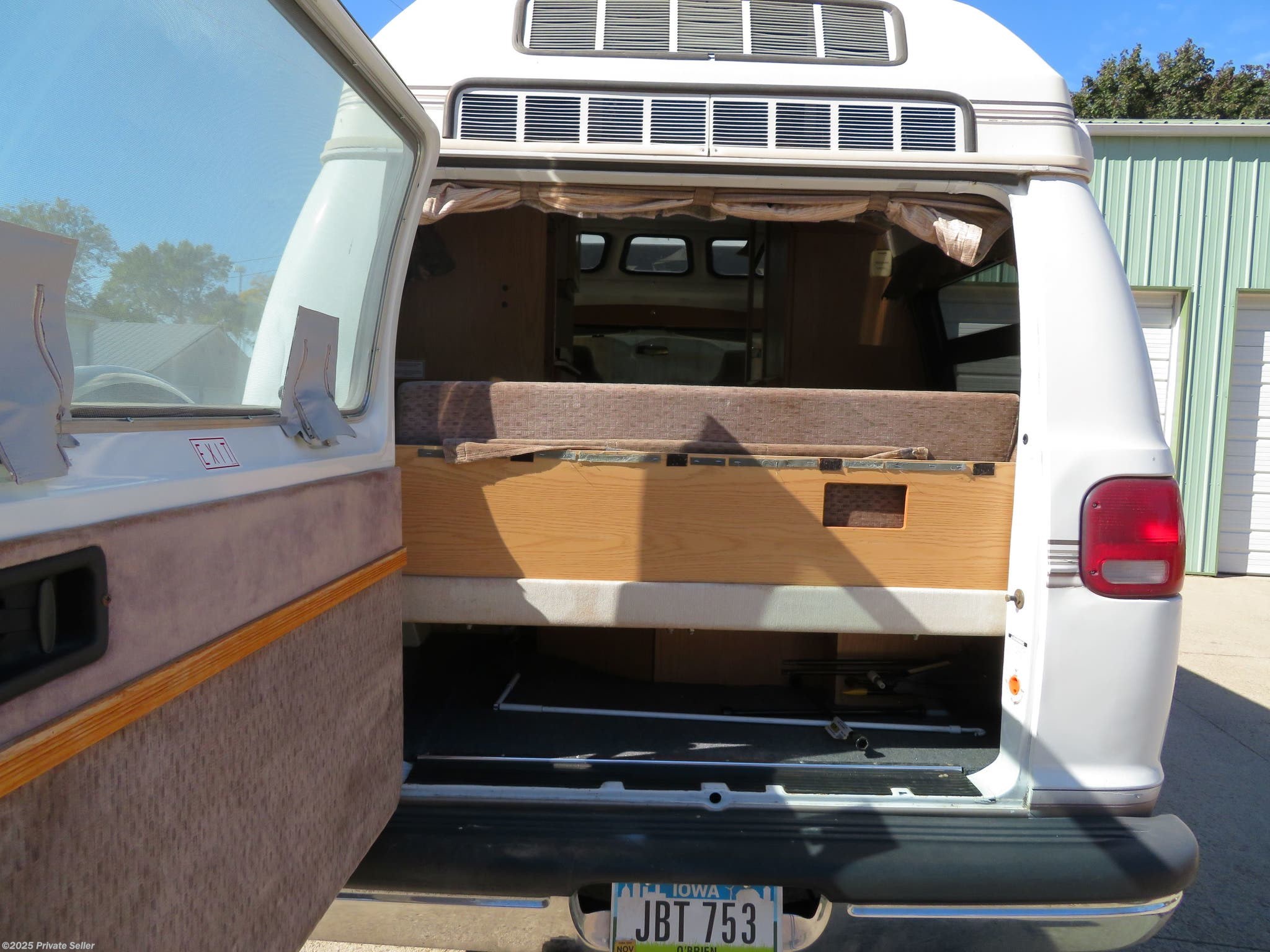 Open rear doors of an RV rental reveal a custom bed platform and under-bed storage, ideal for road trips.. Roadtrek 190 Popular 2010