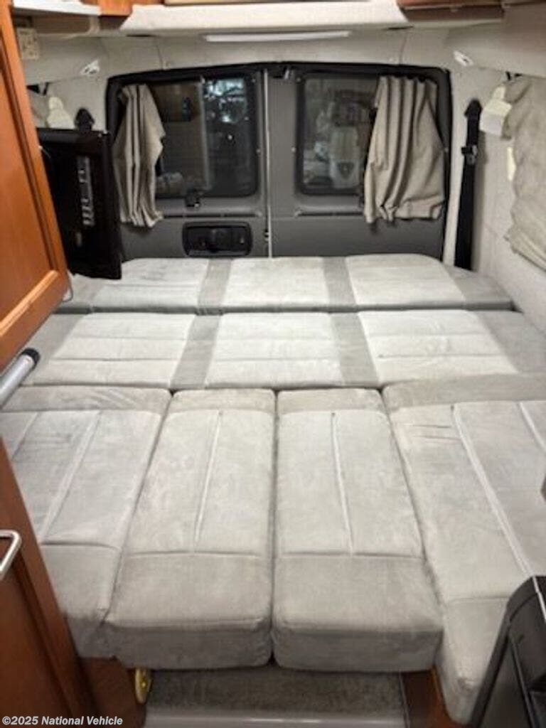 RV rental interior: light gray cushions form a convertible bed/seating area, with rear windows and TV for comfort.. Roadtrek 190 Popular 2010