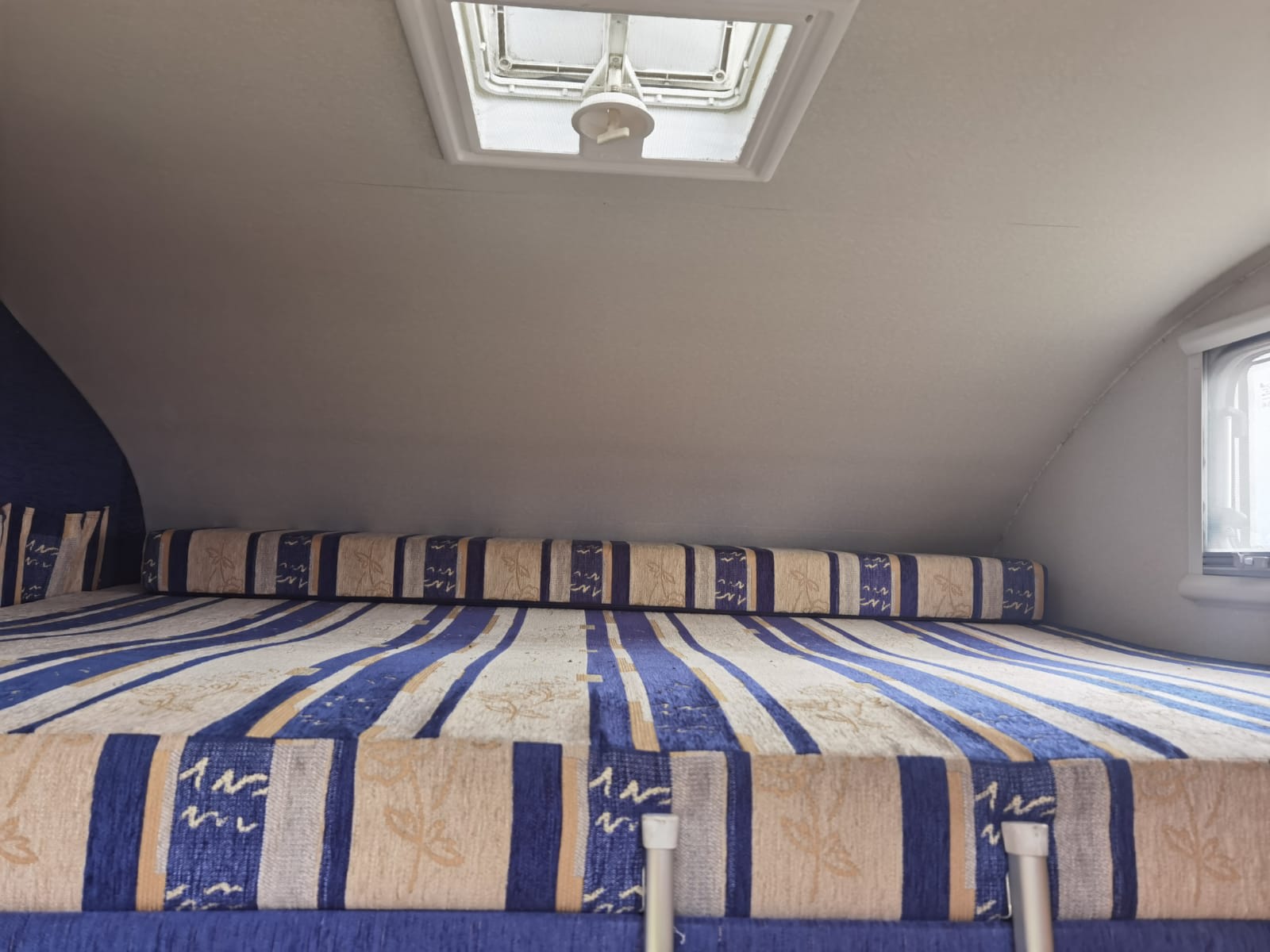 Cozy rv rental interior: blue & beige striped bed with a skylight, perfect for travel.. FIAT McLouis Glen 690g 2005