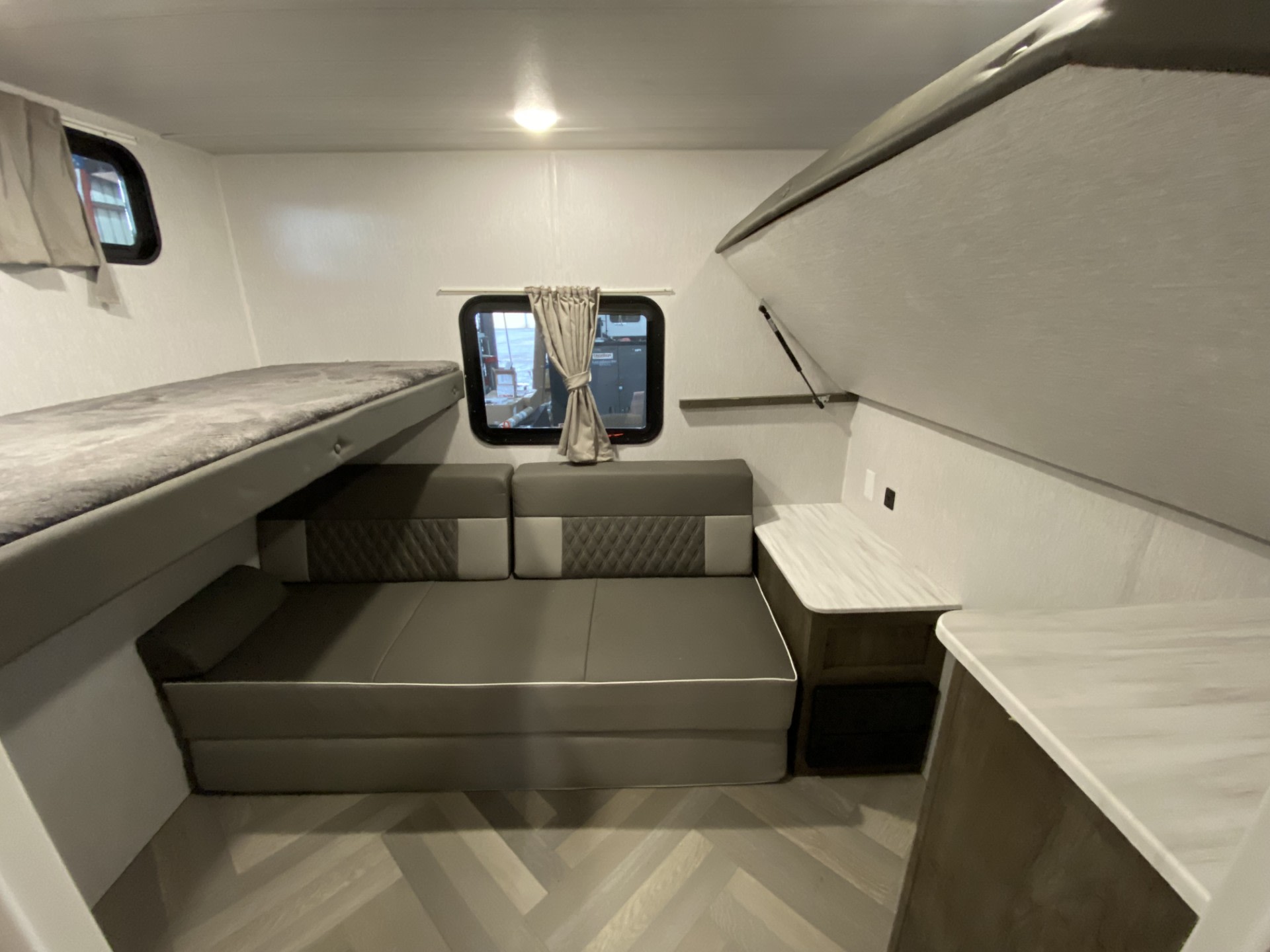 RV rental showing a compact interior with a bunk bed, convertible sofa, and a fold-down upper bunk over counters.. Forest River Wildwood 2022