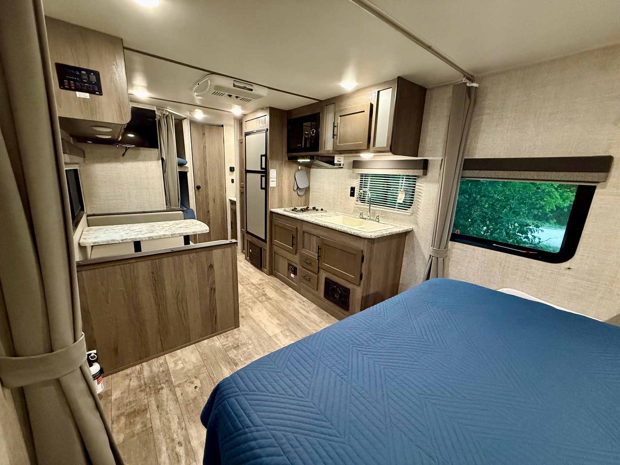 RV rental: Inside a modern travel trailer with a bed, compact kitchen, and dinette, offering a comfortable living space.. Gulf Stream Kingsport 2021
