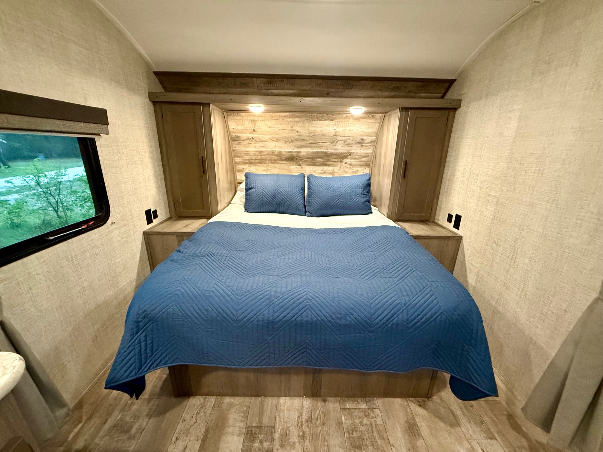 Cozy RV rental bedroom with a comfy bed, wood accents, and a window view. Perfect for travel adventures!. Gulf Stream Kingsport 2021