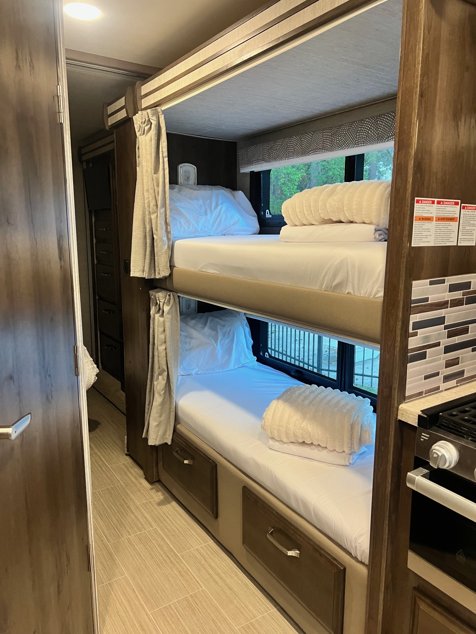 Cozy RV rental bunk beds with fresh white linens, storage drawers, and nearby kitchen setup.. Entegra Coach Esteem 2021