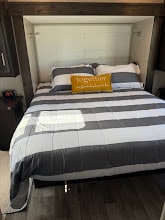 Comfortable RV rental bedroom setup with grey & white striped bedding, perfect for your next travel accommodation.. Jayco Greyhawk 2023