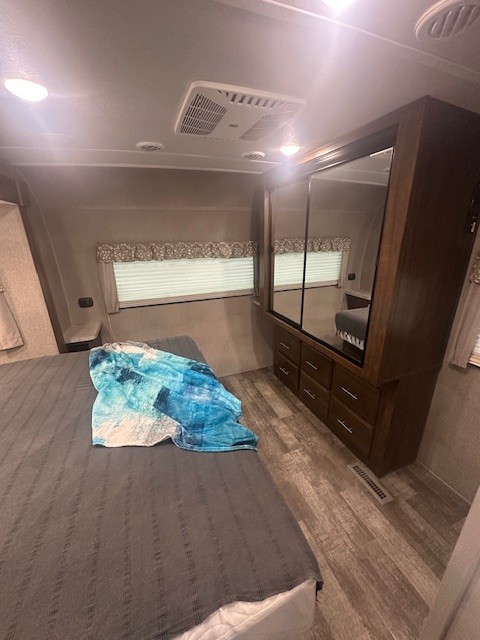 Step inside this cozy RV rental bedroom. It features a spacious bed, mirrored wardrobe, and well-lit modern interior.. Forest River Rockwood 2019
