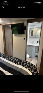 RV rental: This bedroom offers a wall-mounted TV, and an open sliding door leads to a full bathroom with a vanity and toilet.. Keystone Fuzion 2020