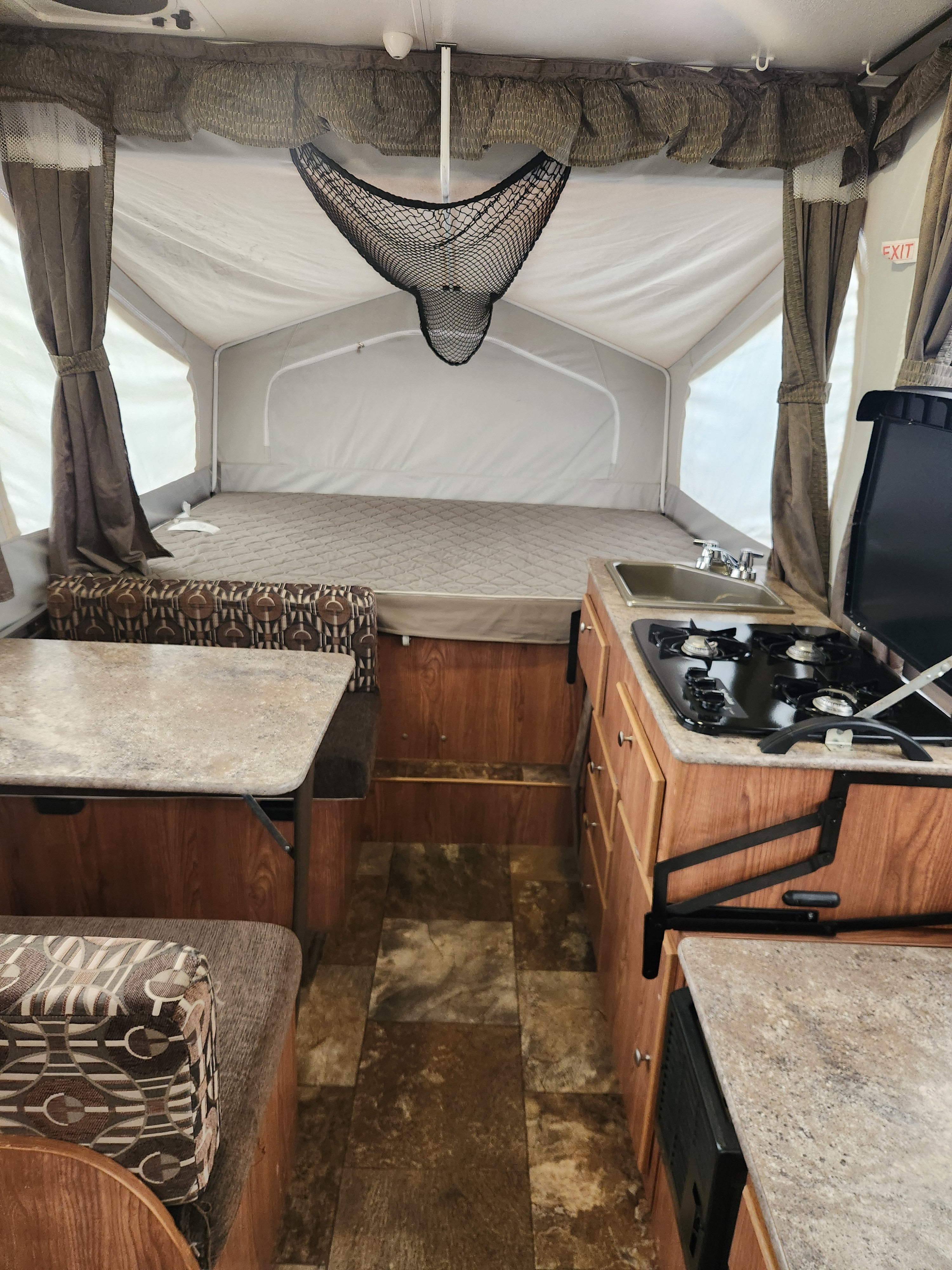 Inside a modern pop-up rv rental, showing a cozy bed, fully equipped kitchen with stove & sink, and dinette area.. Forest River Flagstaff M.A.C. 2016