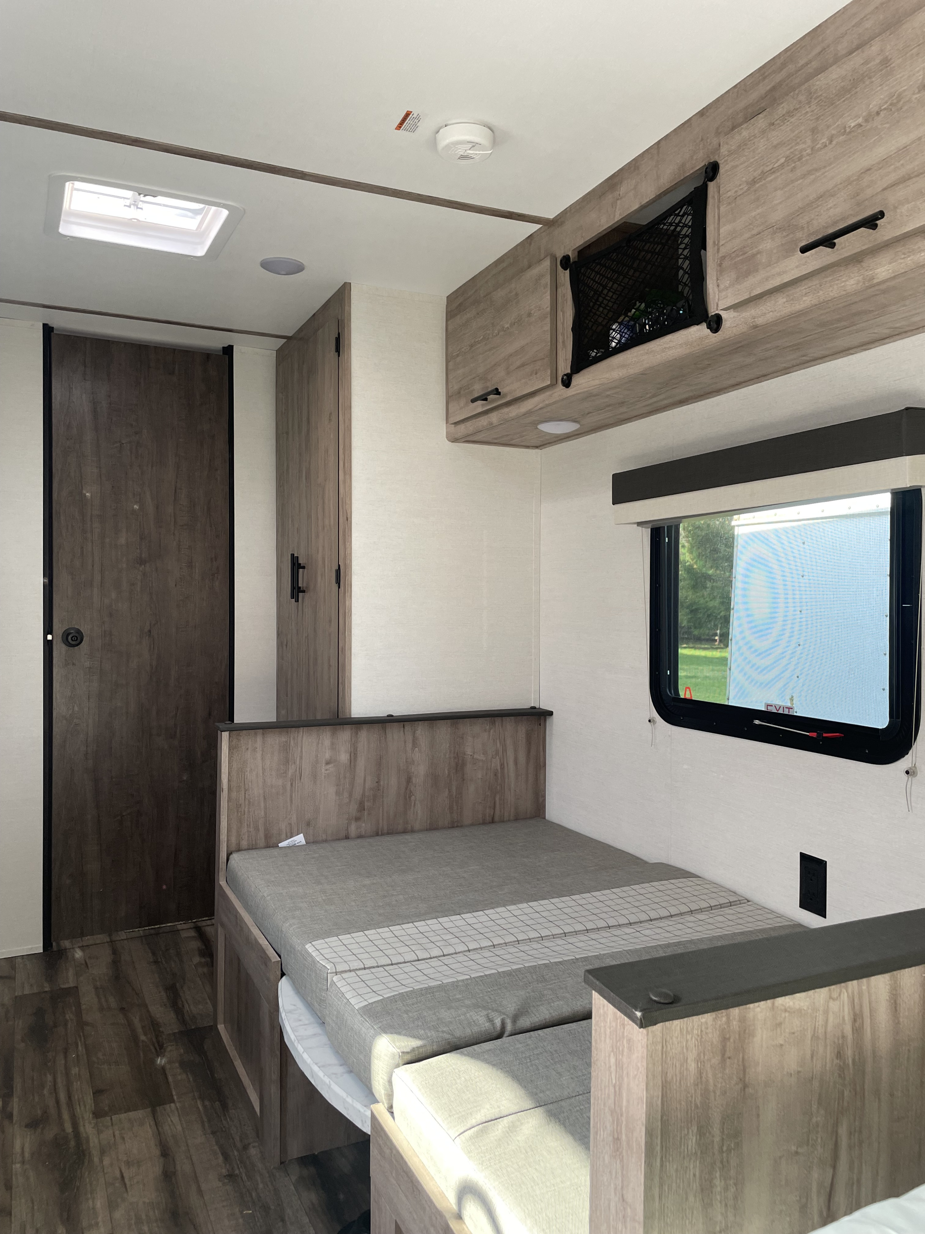 RV rental interior featuring a compact living space with a convertible bed/dinette, overhead storage, and a large window.. Gulf Stream Ameri-Lite 2024