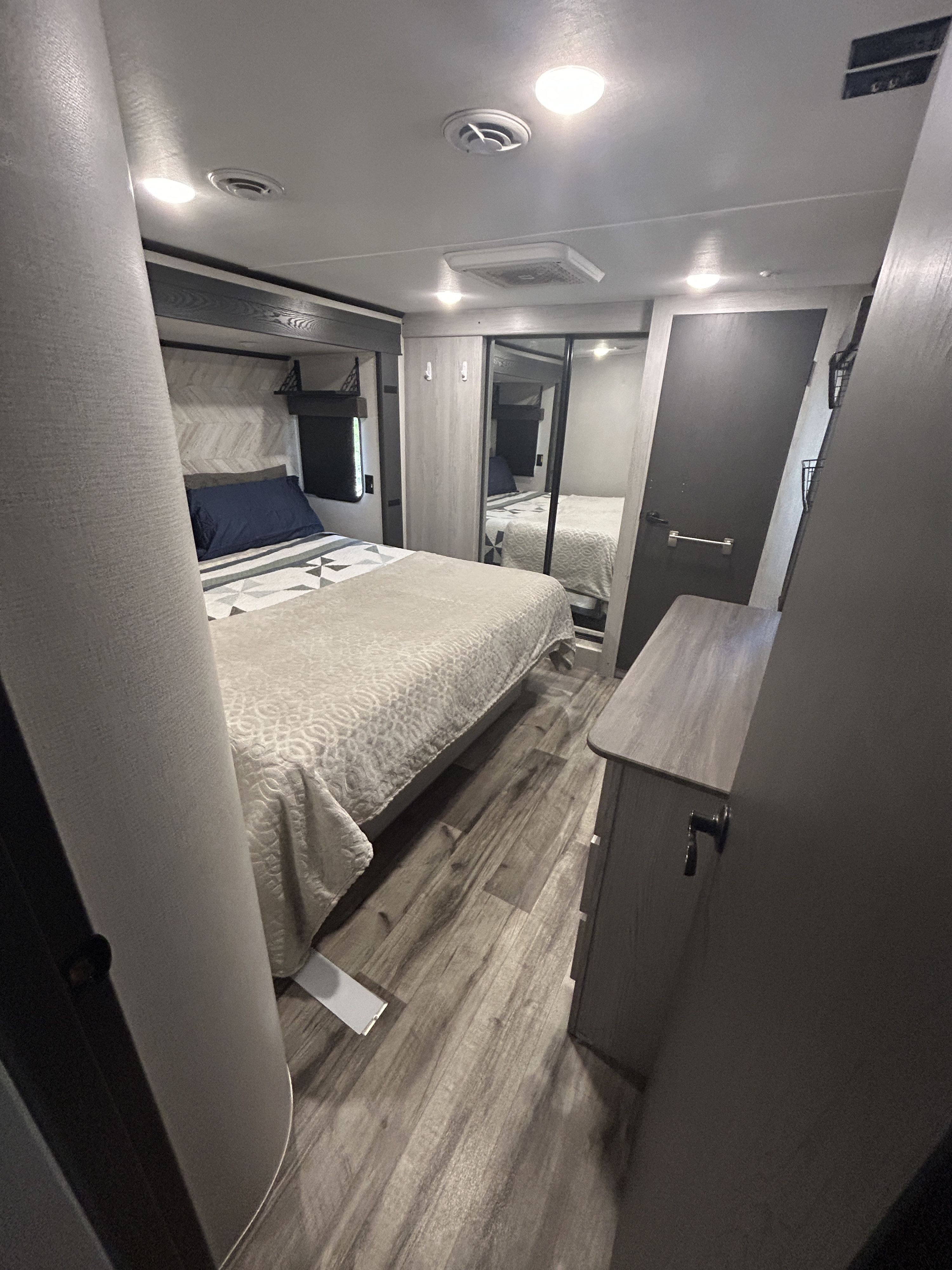 Cozy RV bedroom in an rv rental, featuring a comfortable bed, mirrored wardrobe, and modern mobile living space design.. Keystone RV Montana High Country 2023