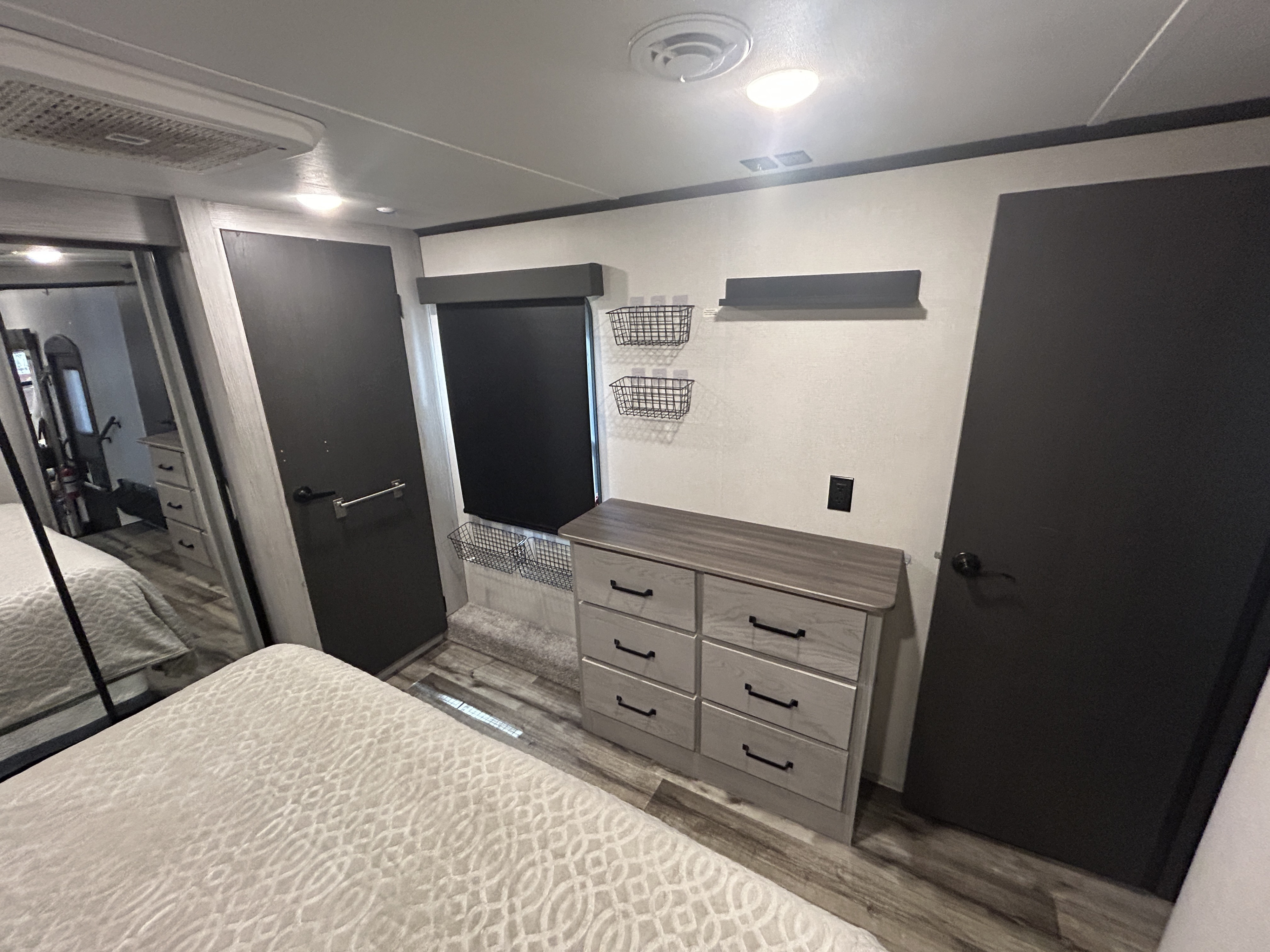 Modern RV rental bedroom: cozy bed, dresser, dual doors, and smart wall storage solutions for compact living.. Keystone RV Montana High Country 2023