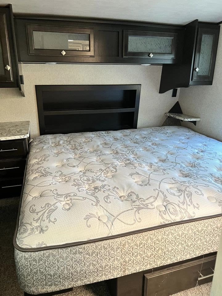RV rental bedroom interior featuring a comfortable queen bed, overhead cabinets, and built-in headboard storage.. Heart Land Road Warrior 2017