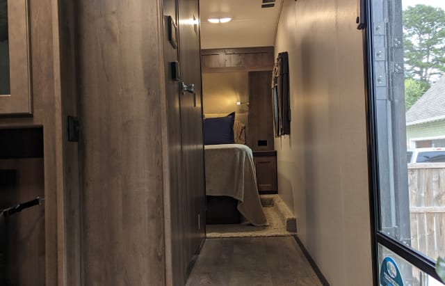Inside this cozy RV rental, a hallway leads to a private bedroom with a comfortable bed and warm lighting.. Forest River Wildcat Ultra Lite 2019
