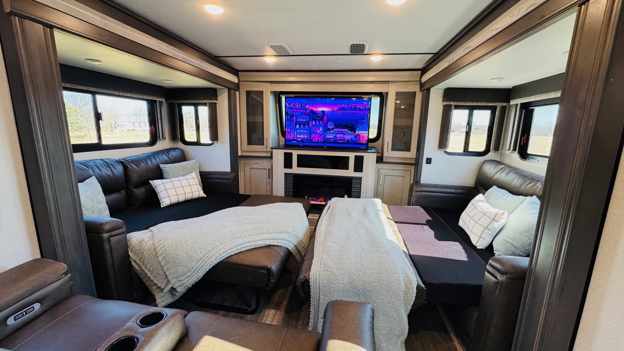 Comfortable RV rental interior: large living area with pull-out couches, soft blankets, a TV, and fireplace.. Keystone RV Montana High Country 2021