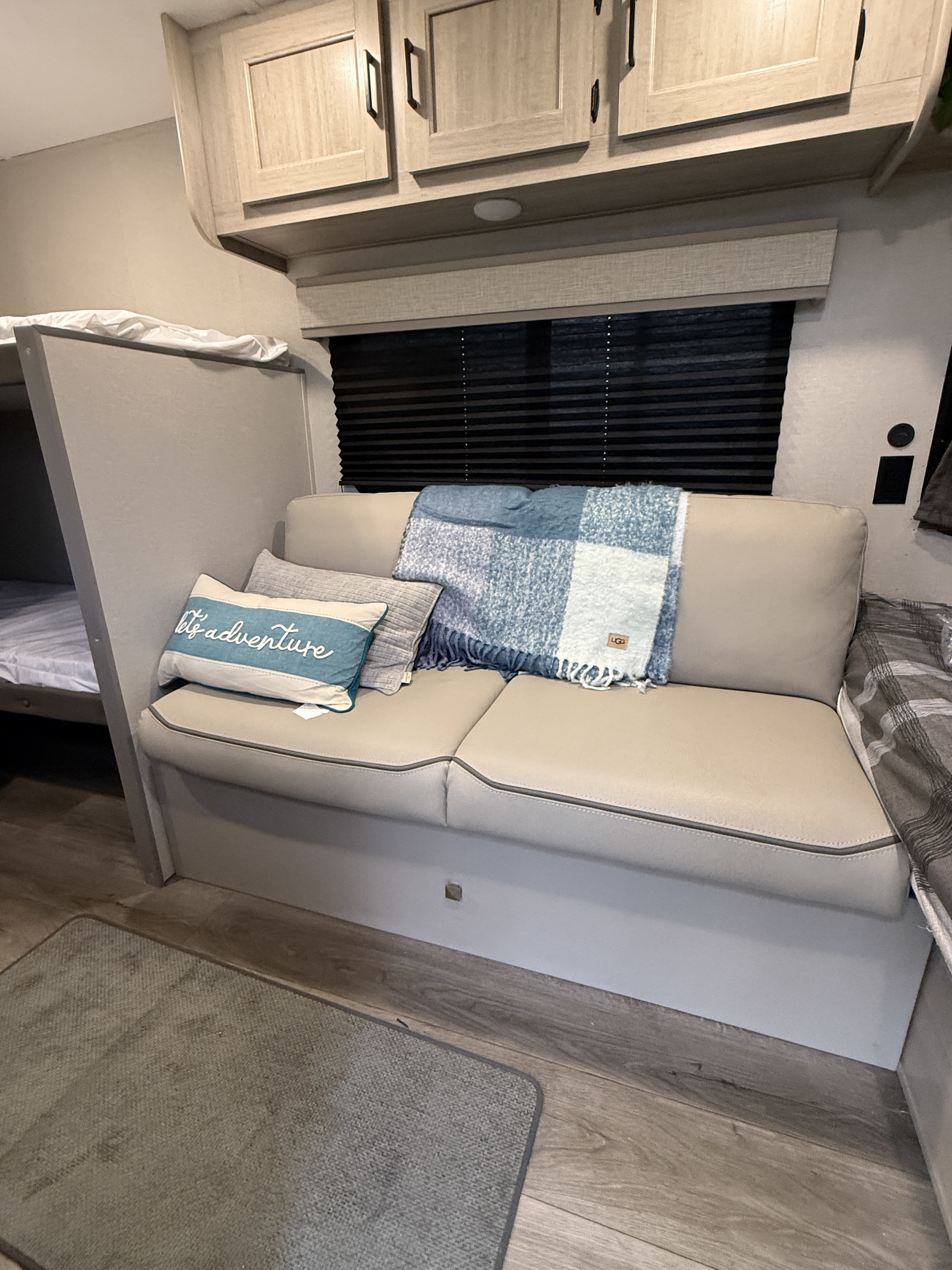 Inviting rv rental interior featuring a beige dinette sofa with pillows, blue blanket, and a bunk bed.. Forest River Coachmen Catalina Summit 2024