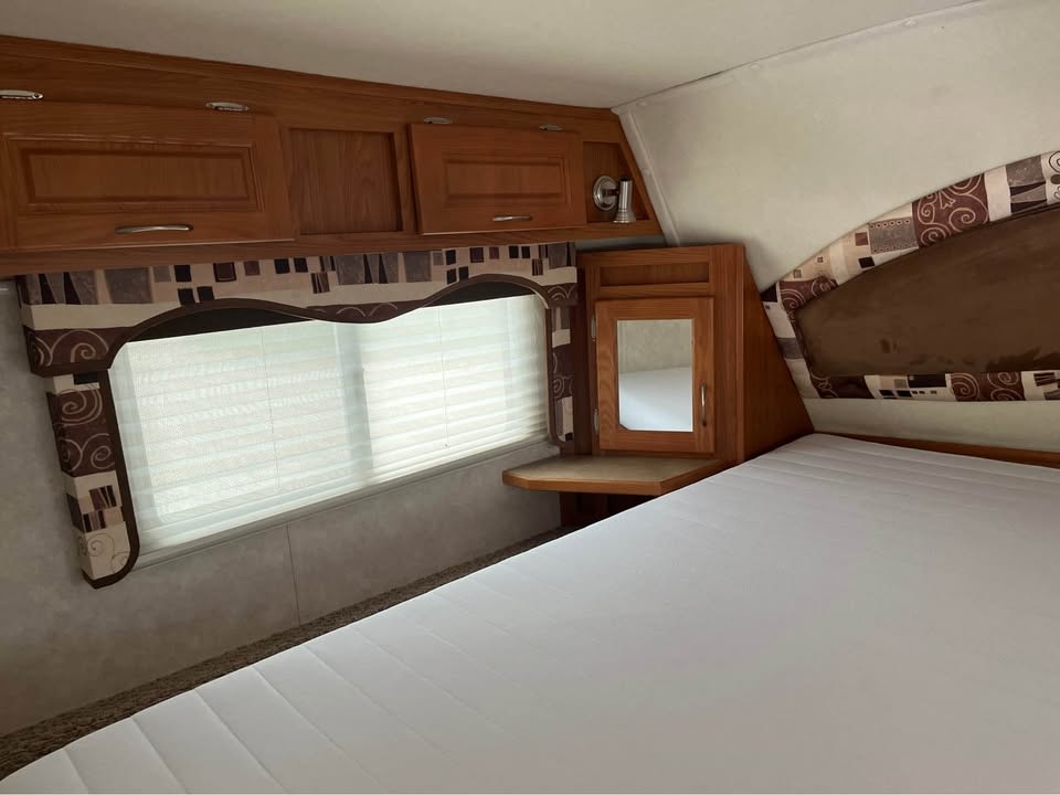 Cozy RV rental bedroom with comfortable bed, overhead cabinets, and a window, ideal for your next adventure.. Kodiak Kodiak Fifth Wheel 2006