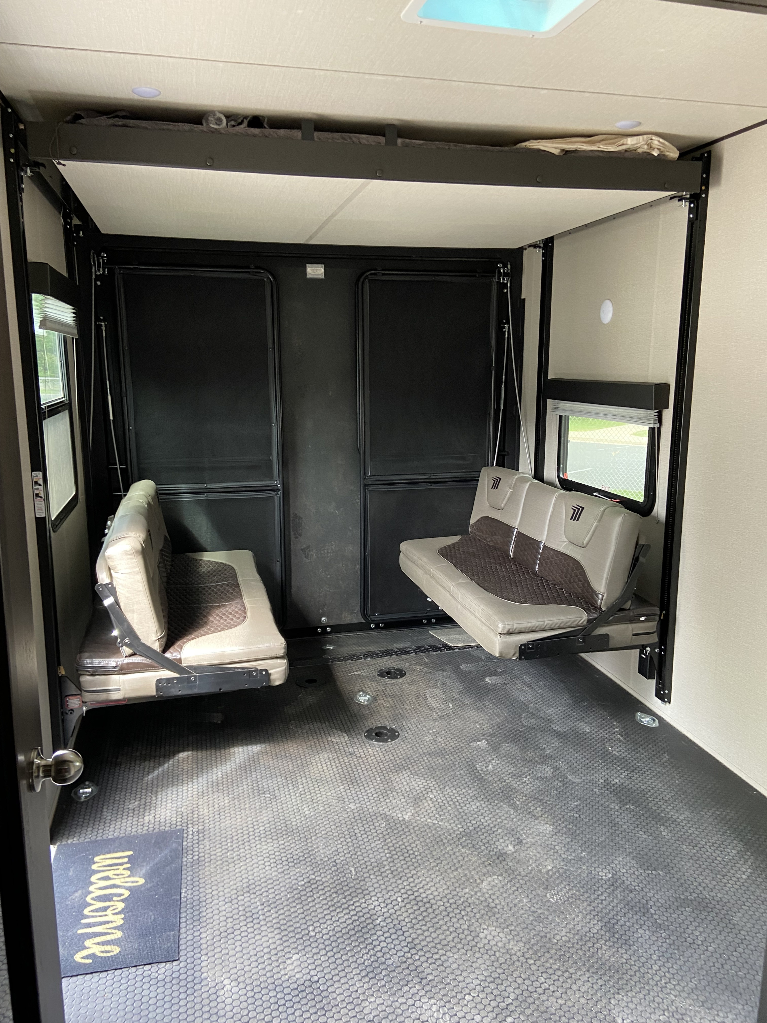 Inside an RV rental toy hauler garage: convertible seating, stowed upper bunk, and durable floor. Ready for gear & guests!. Grand Design Momentum 2022
