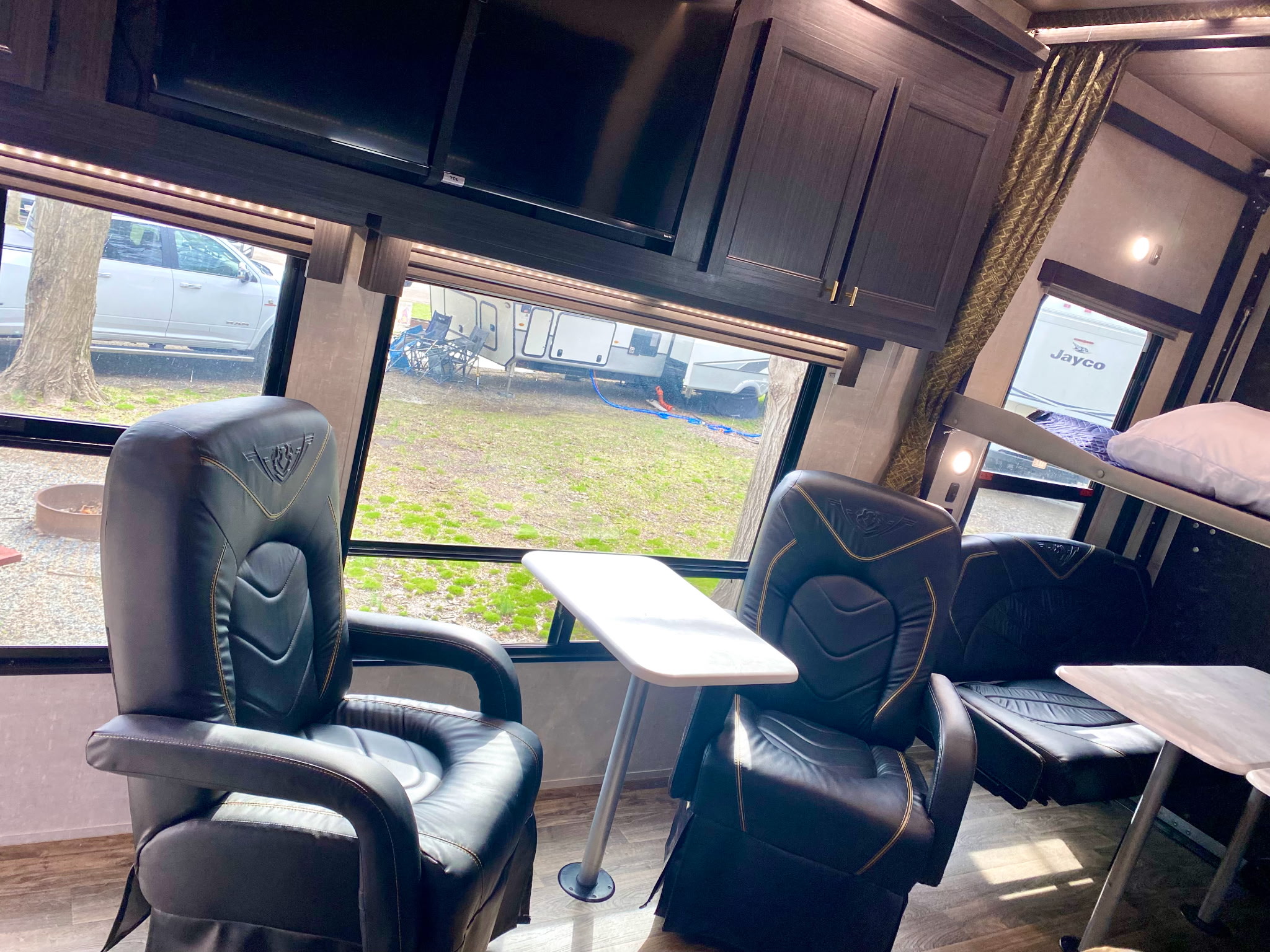 Comfortable RV rental interior featuring two recliners, TV, bunk beds, and a view of the campsite outside.. Eclipse Recreational Vehicles Attitude 2023