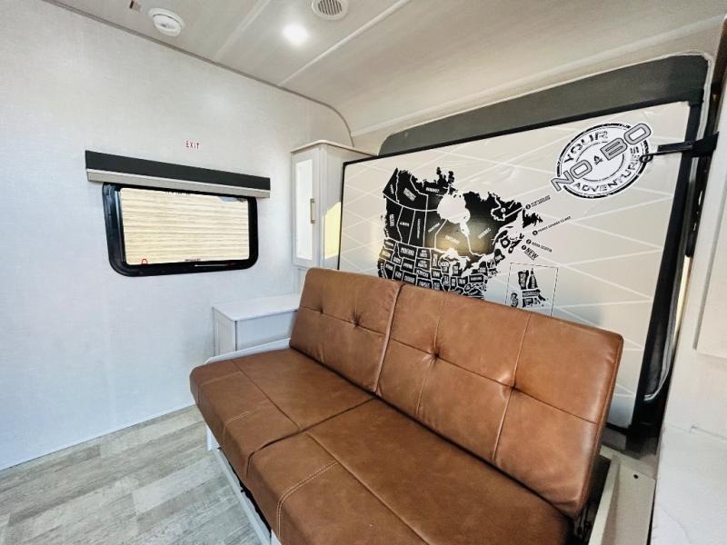 Spacious RV rental living area with a brown futon, large map wall, and window, ready for adventure.. Forest River No Boundaries NoBo 20.3 2025