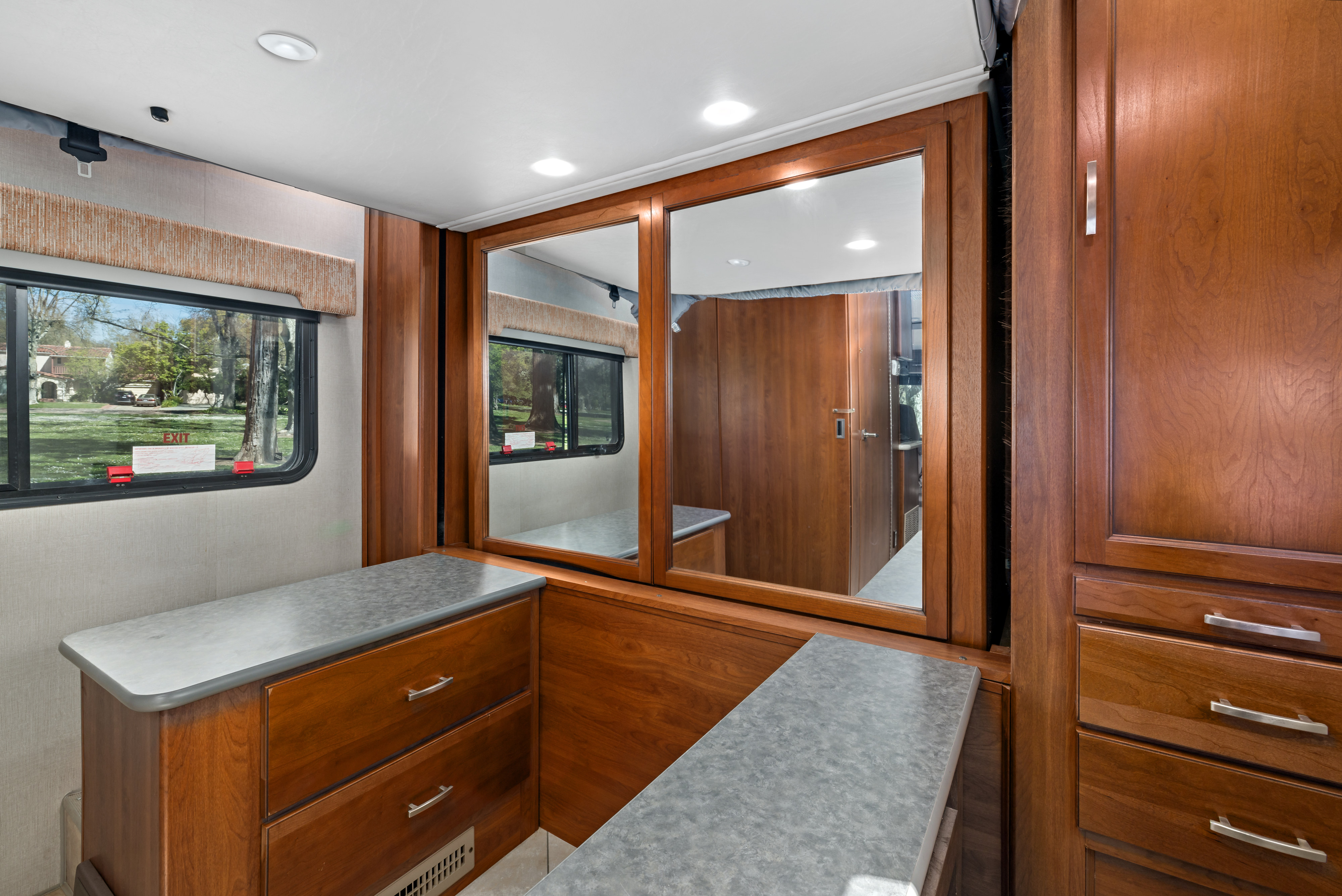 Spacious RV rental interior with rich wood cabinets, sleek grey countertops, and a window view. Ideal for your next adventure.. Monaco Trek 26HMD 2016