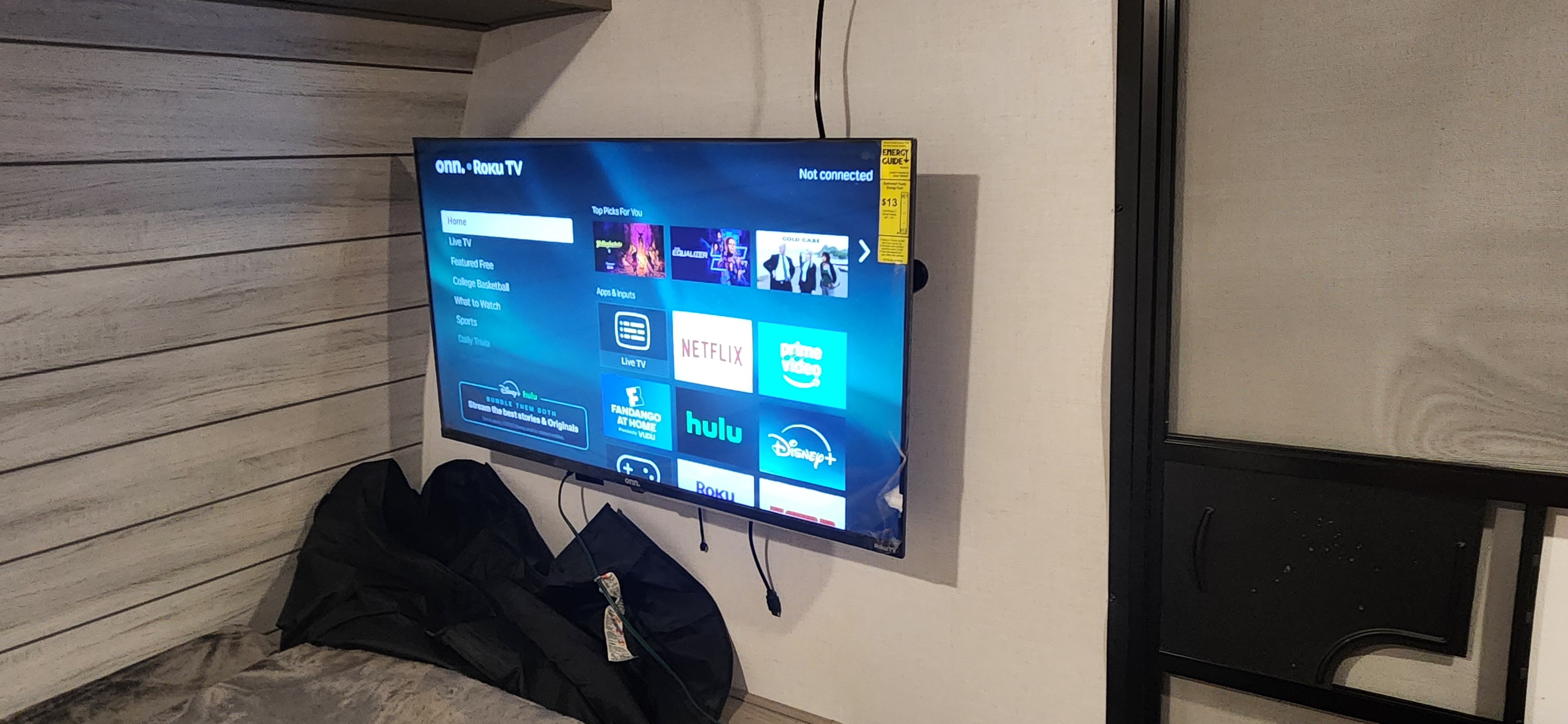 An RV rental interior shows a mounted Onn. Roku TV displaying streaming apps, perfect for onboard entertainment.. coleman Coleman Lantern LT 17B 2024