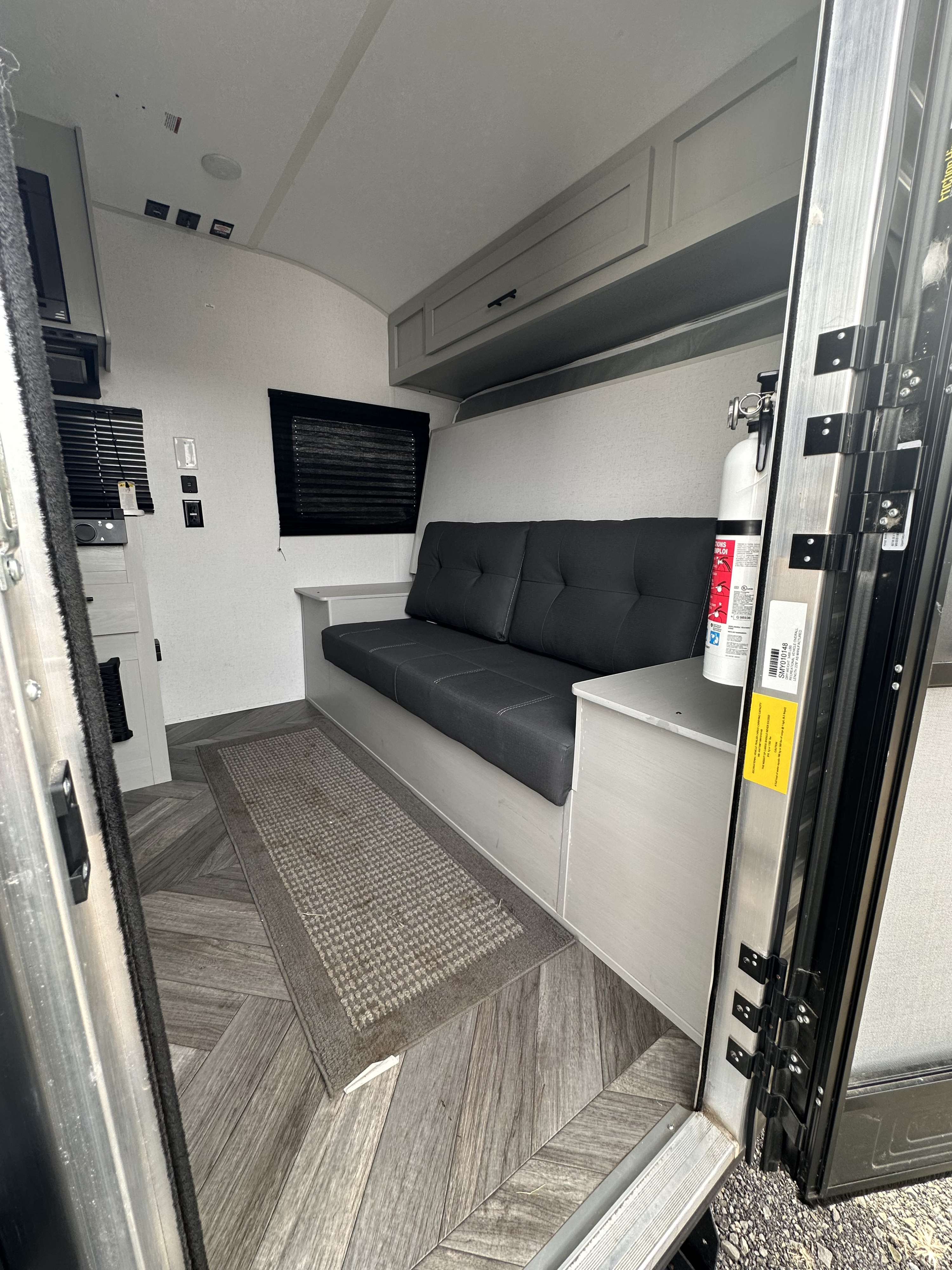RV rental interior showcasing a gray convertible sofa, light overhead cabinets, and patterned wood-look flooring.. Forest River Salem FSX 2022