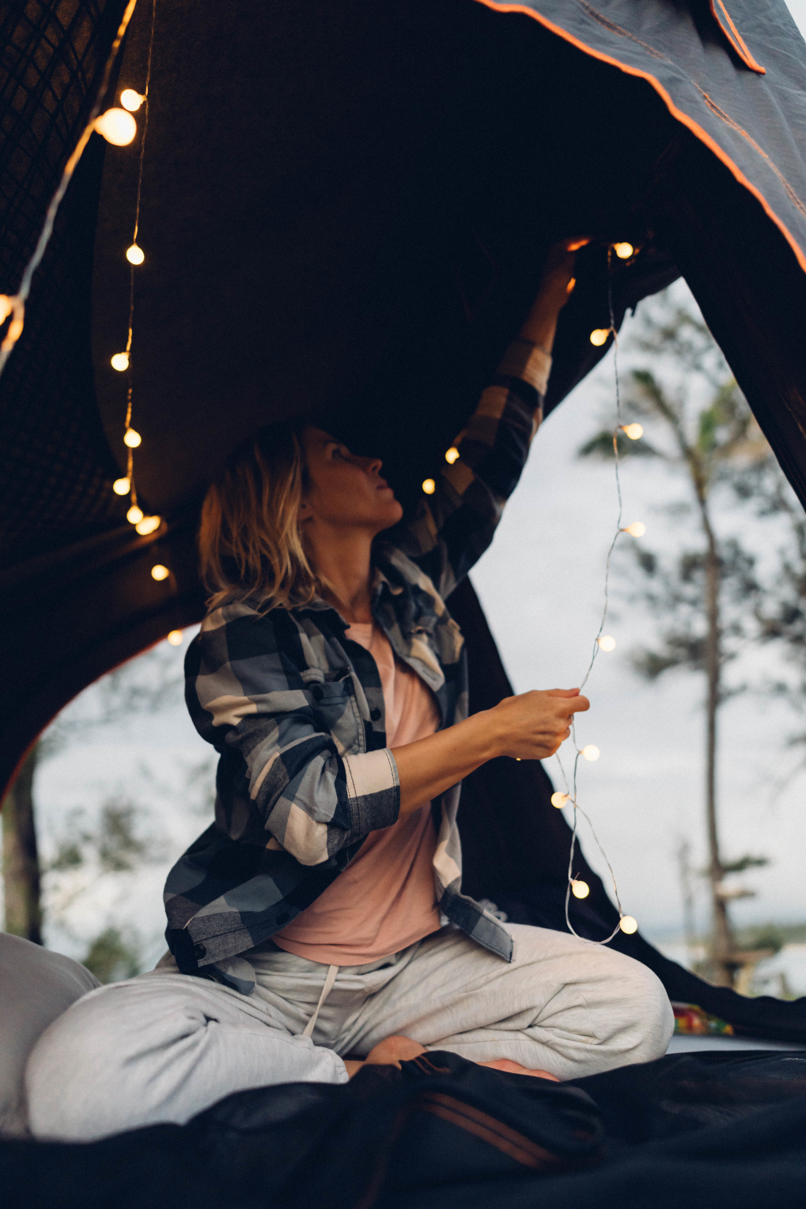 Woman inside a dark camping tent, stringing glowing lights. Creates a warm, inviting space for an RV rental outdoor adventure.. Toyota FJ Cruiser 2007