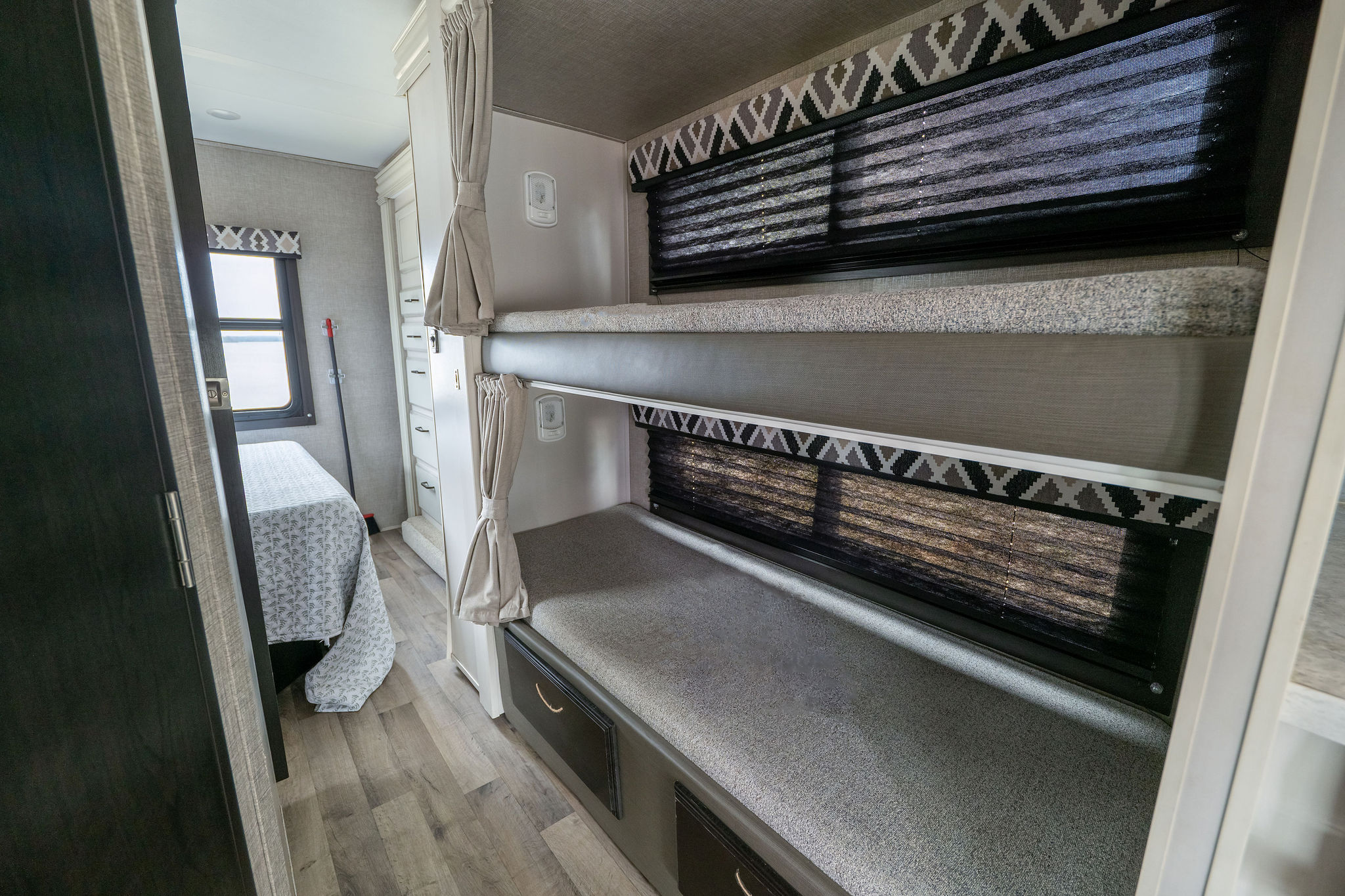 Explore this RV rental's modern interior with two bunk beds (top one visible), a cozy bedroom, and floor-level storage drawers.. Jayco Redhawk 2022