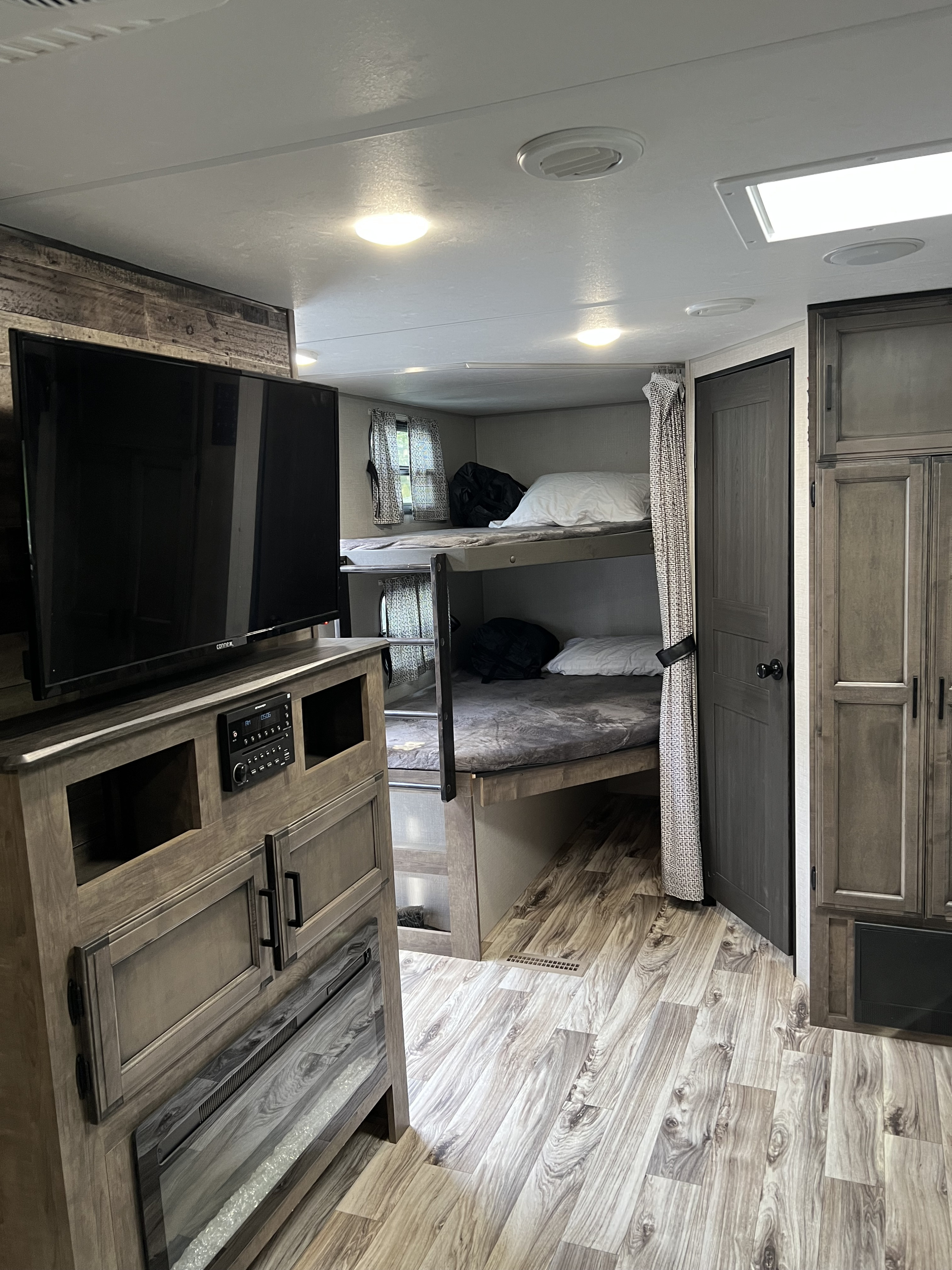 RV rental interior: living space with TV, entertainment center, electric fireplace, and bunk beds.. Venture Stratus 2021