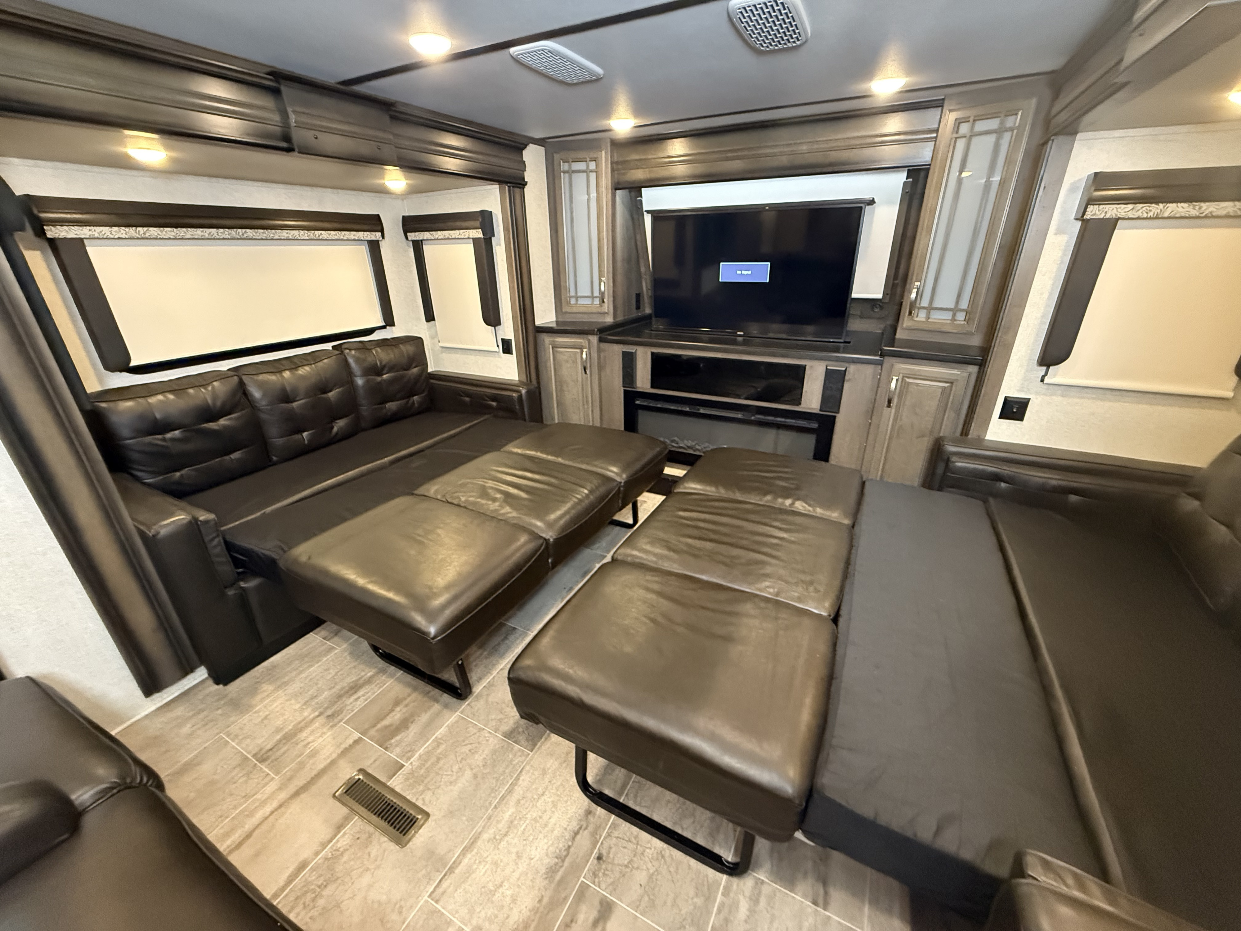 Spacious RV rental living room featuring a convertible sofa bed, TV, and fireplace for comfortable stays.. Keystone RV Montana 20th Anniversary 2019