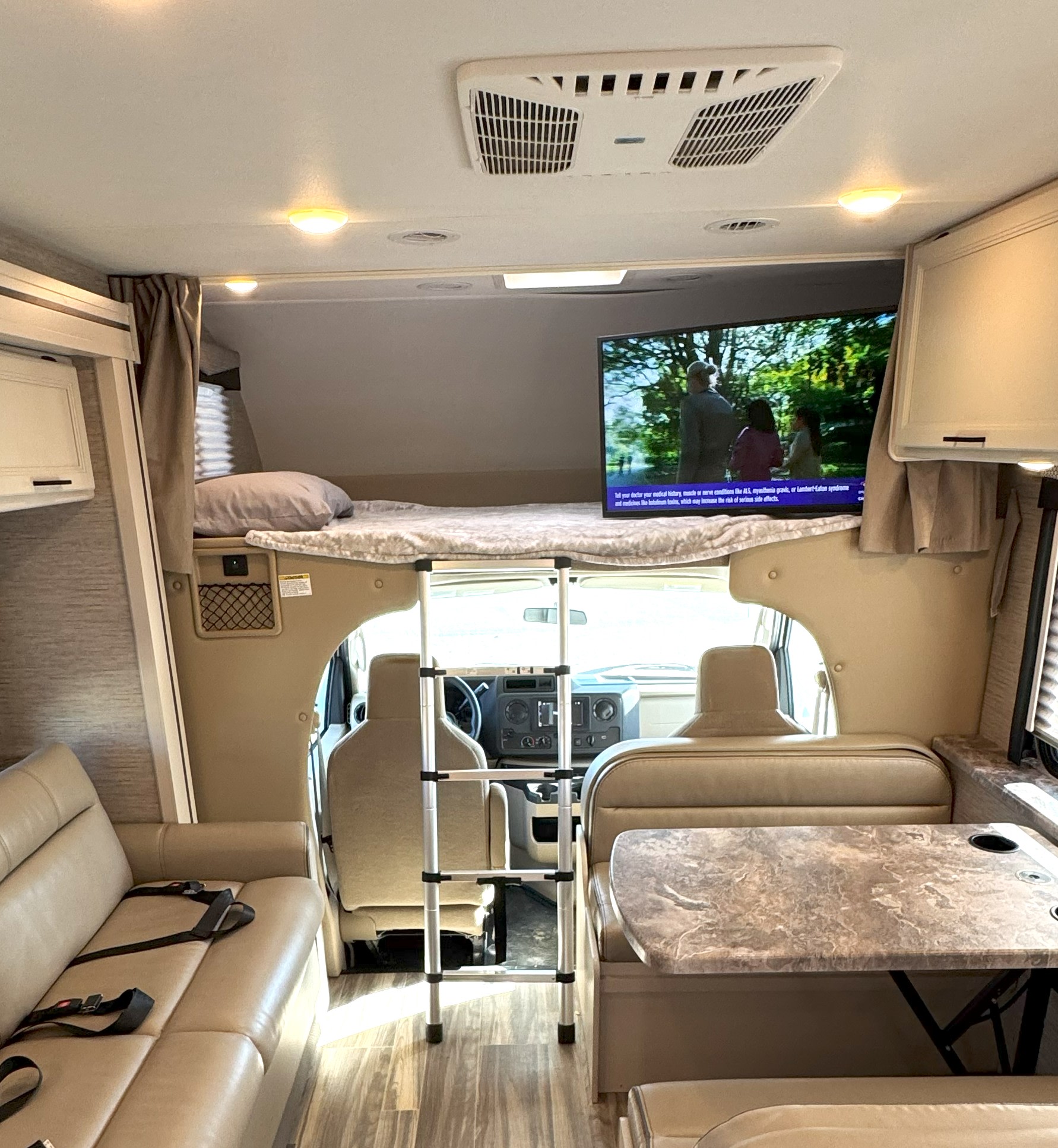 Step inside this spacious RV rental featuring a cozy bunk, dinette, sofa, and TV, perfect for travel living.. Thor Motor Coach Freedom Elite 2023