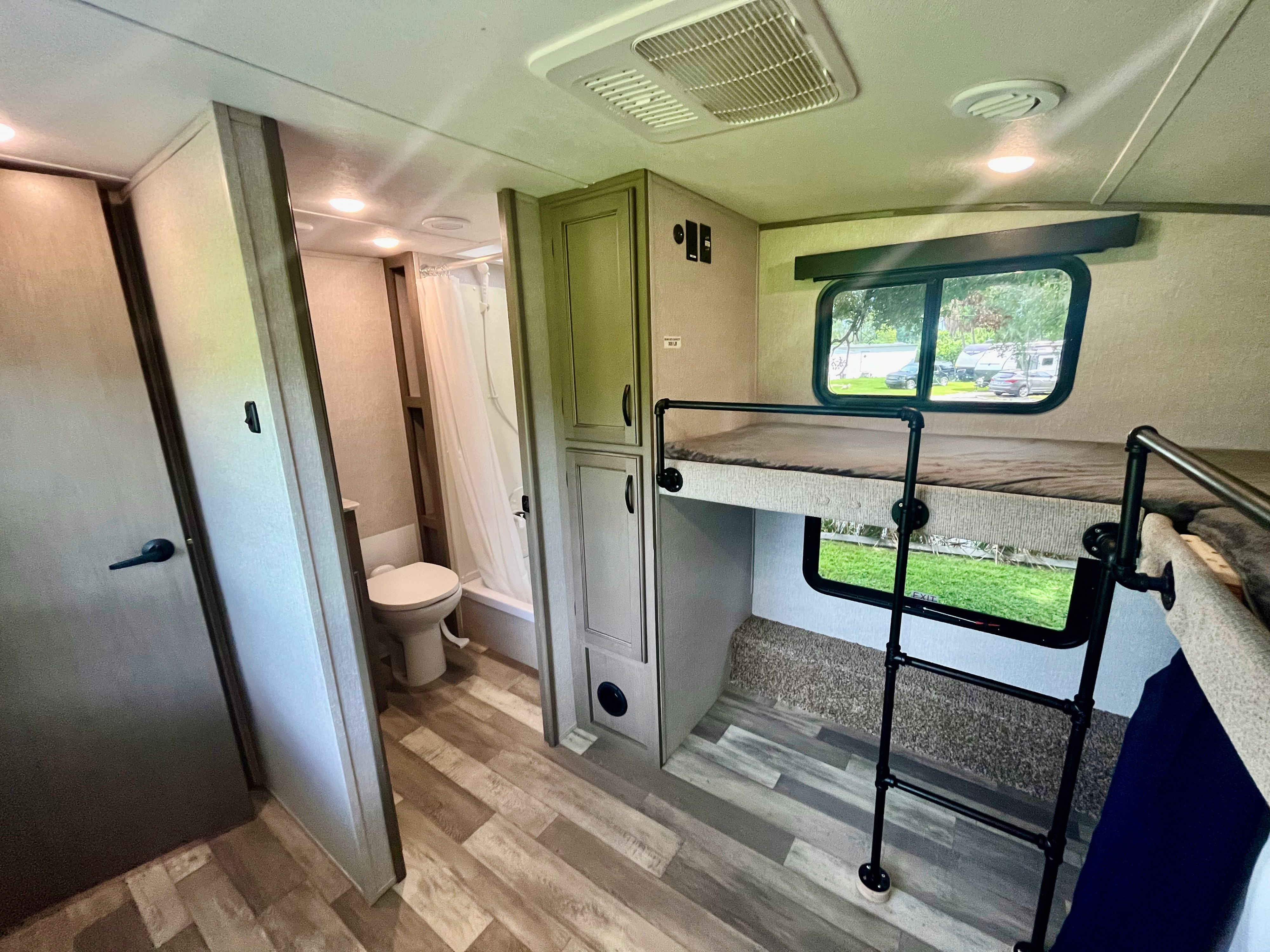 An RV rental interior showcasing bunk beds with a ladder, a compact bathroom, and practical storage cabinets.. Forest River Coachmen Chaparral 2023