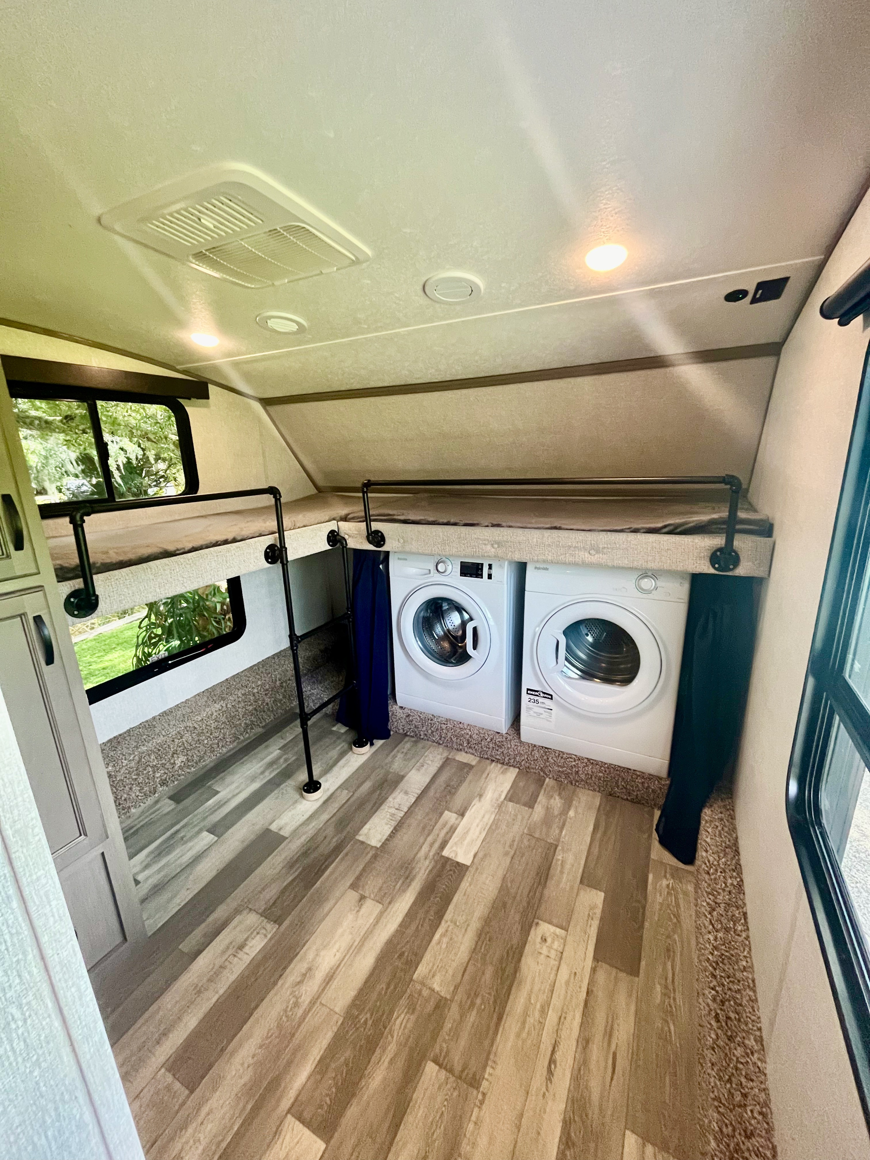 RV rental: Bunk beds above compact washer/dryer units, with wood-look flooring and a small access ladder.. Forest River Coachmen Chaparral 2023