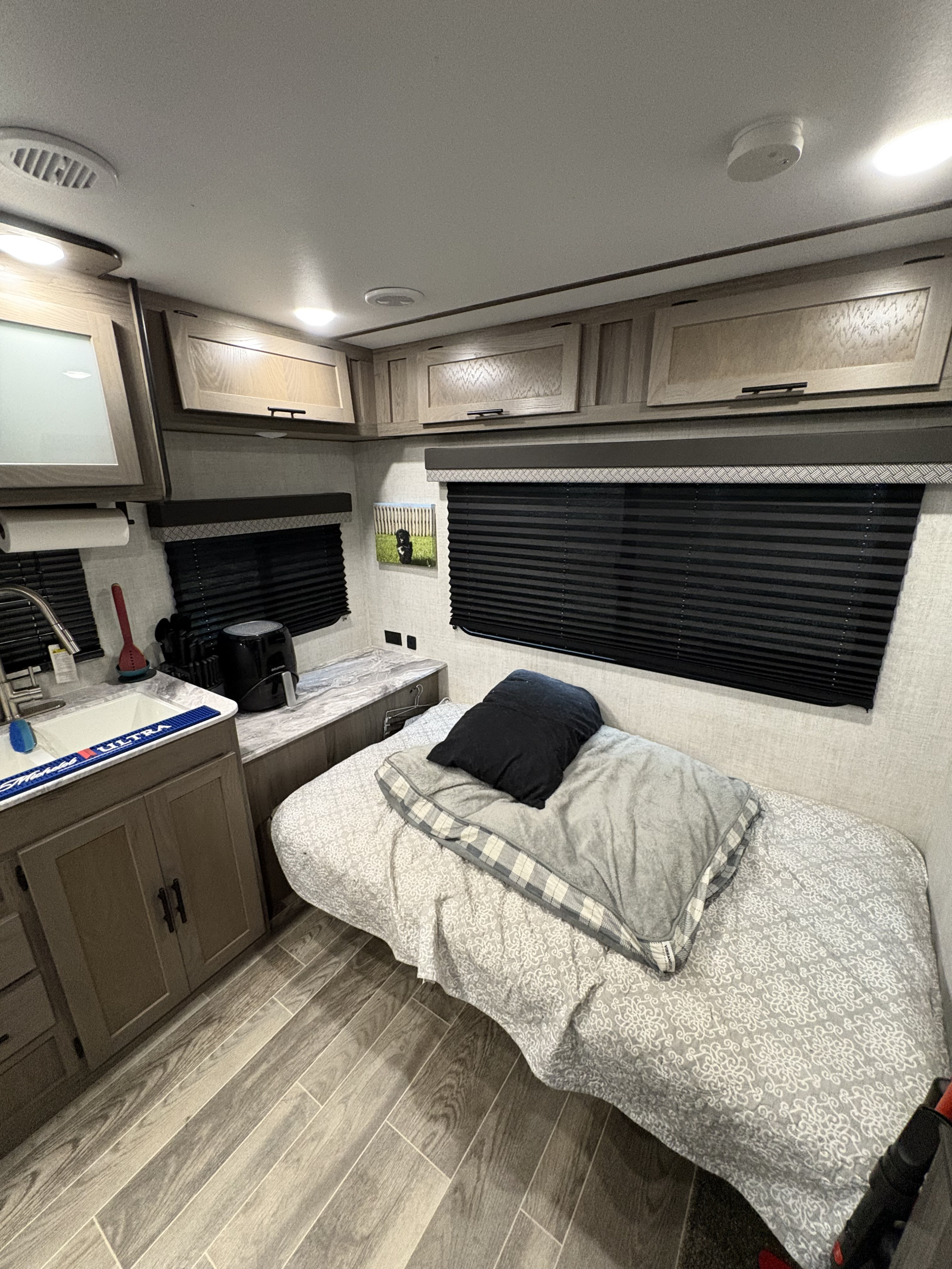 Modern RV rental interior showing a compact bedroom with bed, sink, and wood cabinets. A cozy, functional space for travel.. Gulf Stream Ameri-Lite 2022
