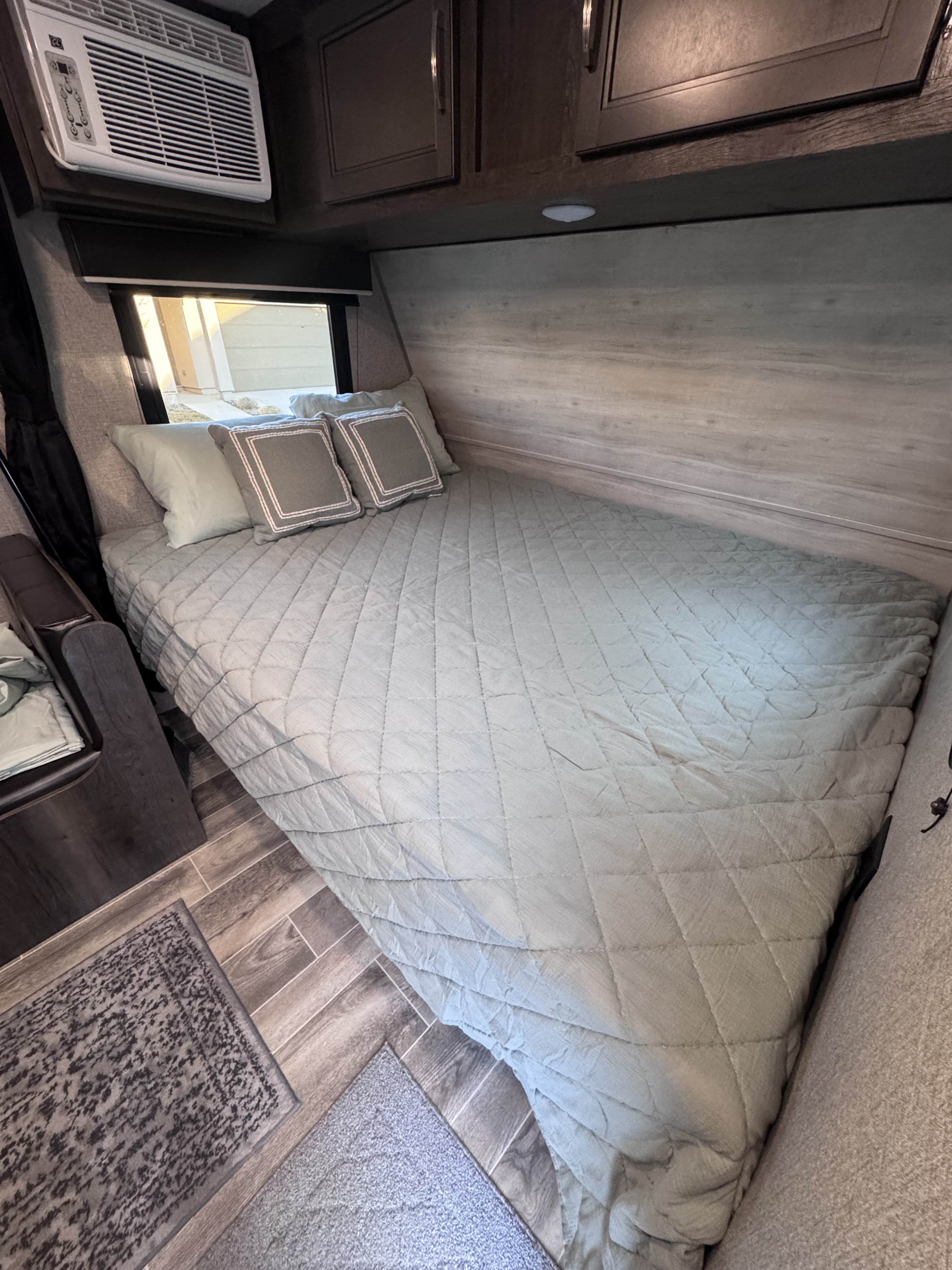 Cozy RV rental bedroom featuring a light green quilted bed, overhead AC, and modern cabinetry.. Jayco Jay Flight SLX Baja Edition 2021
