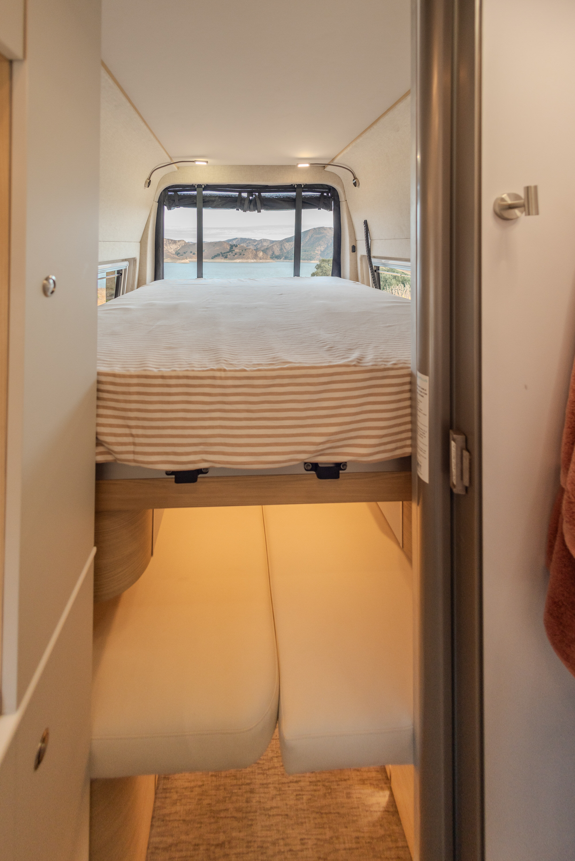 Relax in your rv rental with a stunning lake view from the comfortable bed. Perfect for scenic travel and cozy glamping.. Noovo Plus 2025