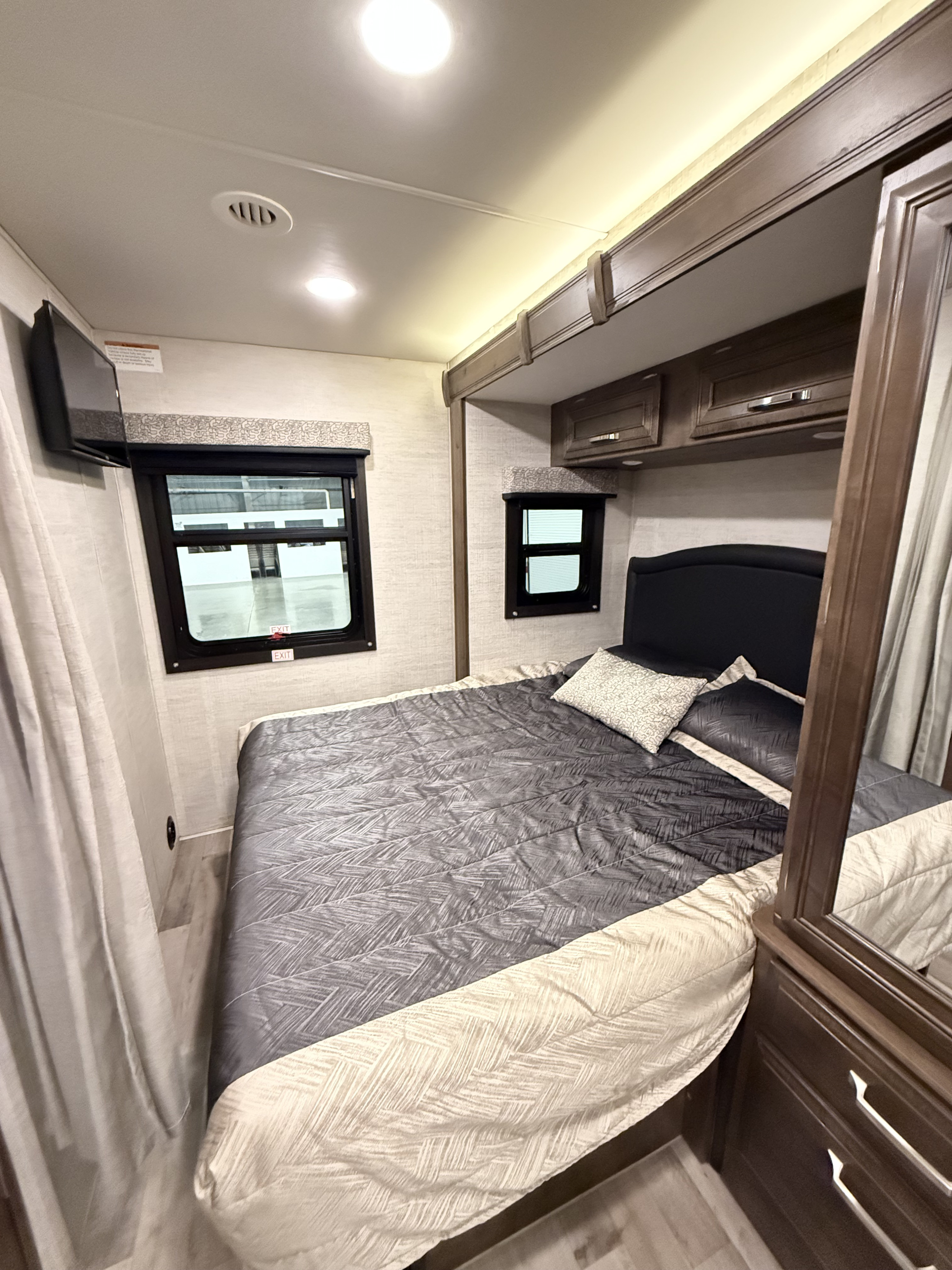 Spacious rv rental bedroom featuring a queen bed, overhead storage, TV, and windows.. Jayco Melbourne 2021