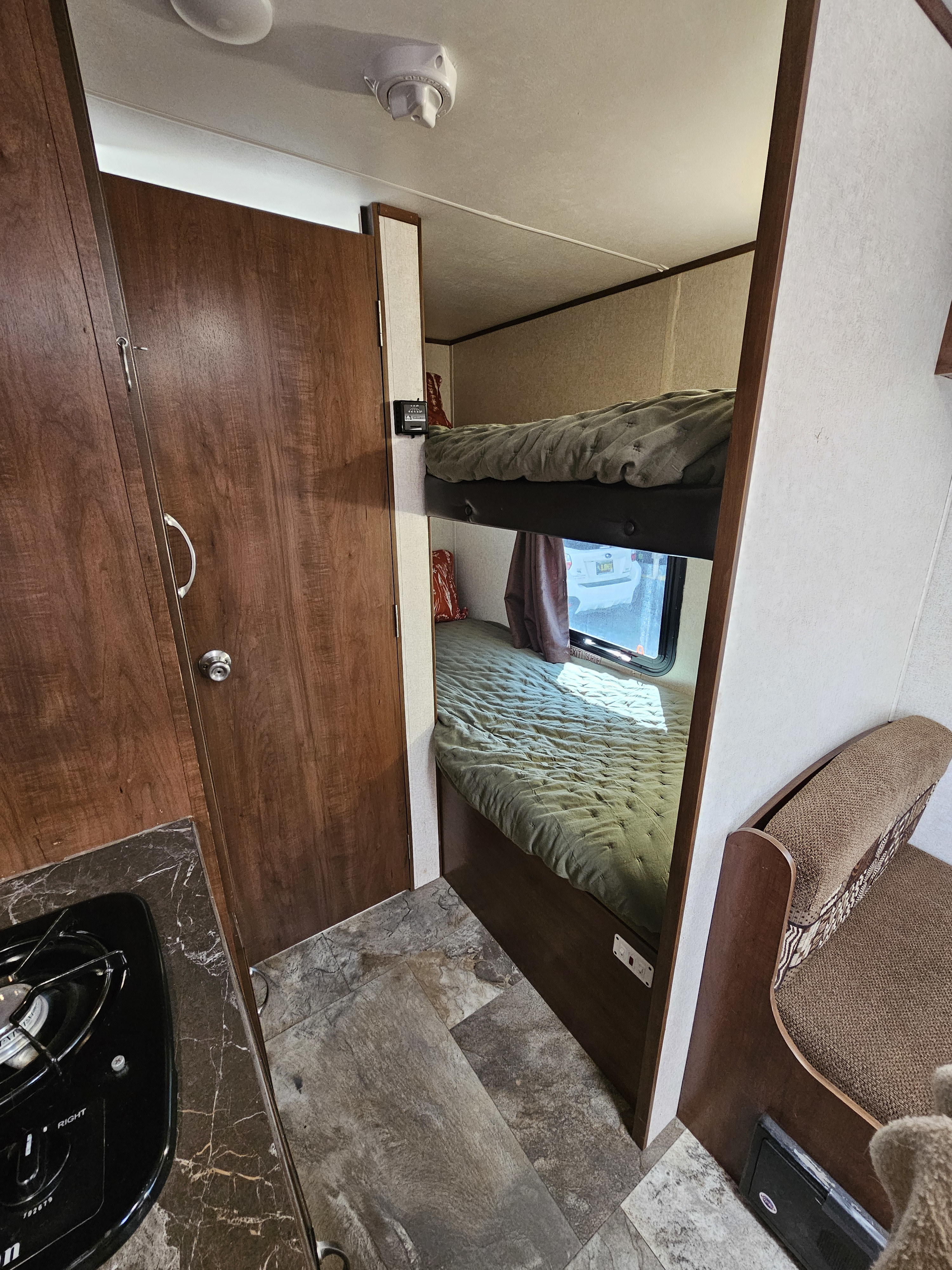 This RV rental interior features cozy bunk beds, a compact kitchen with a stovetop, and a comfortable seating area.. Jayco Jay Flight SLX Baja Edition 2017