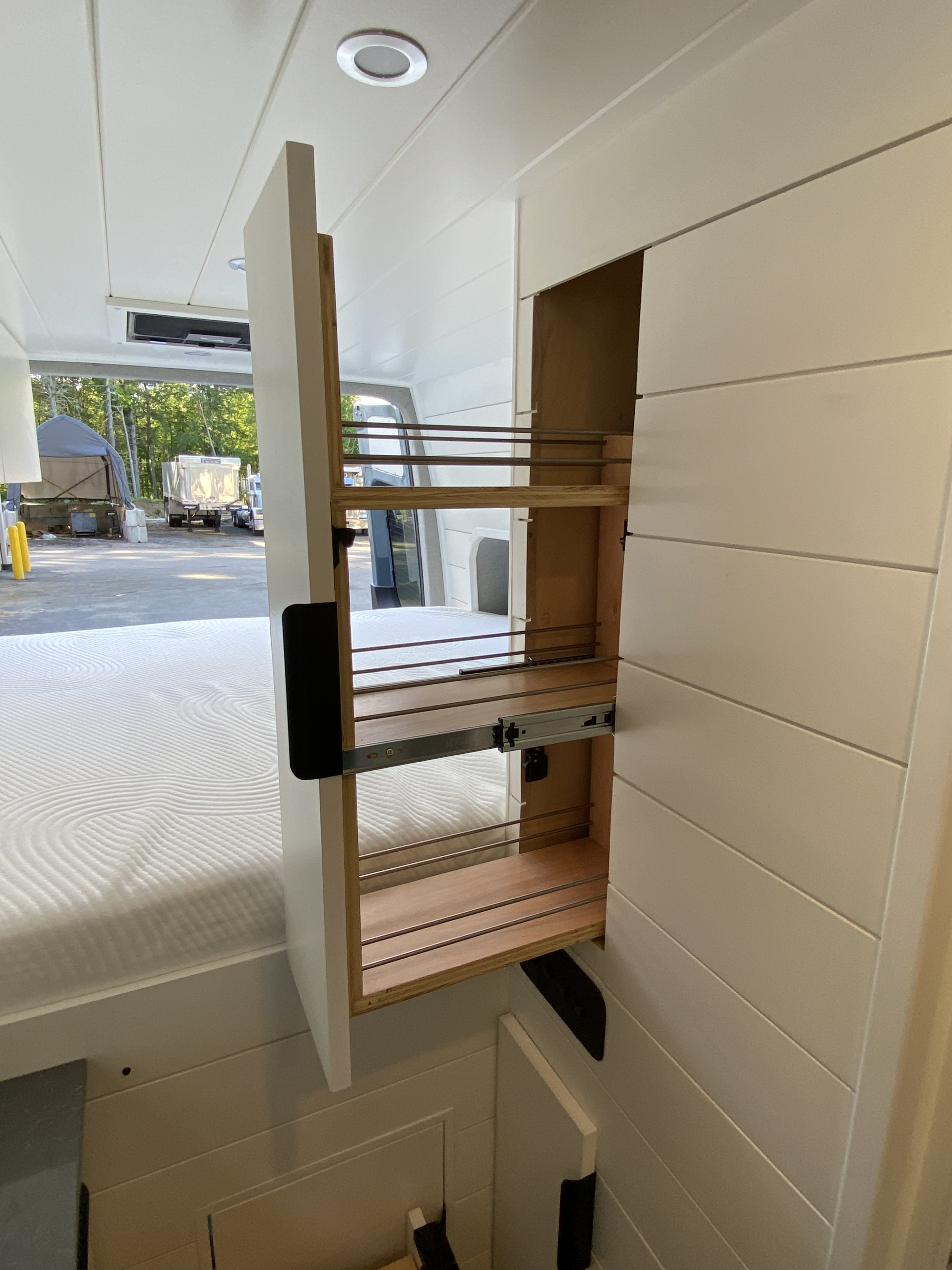 RV rental's smart interior shows a pulled-out pantry storage unit, white shiplap walls, and a comfy bed. Perfect for travel.. Mercedes-Benz Sprinter 2021