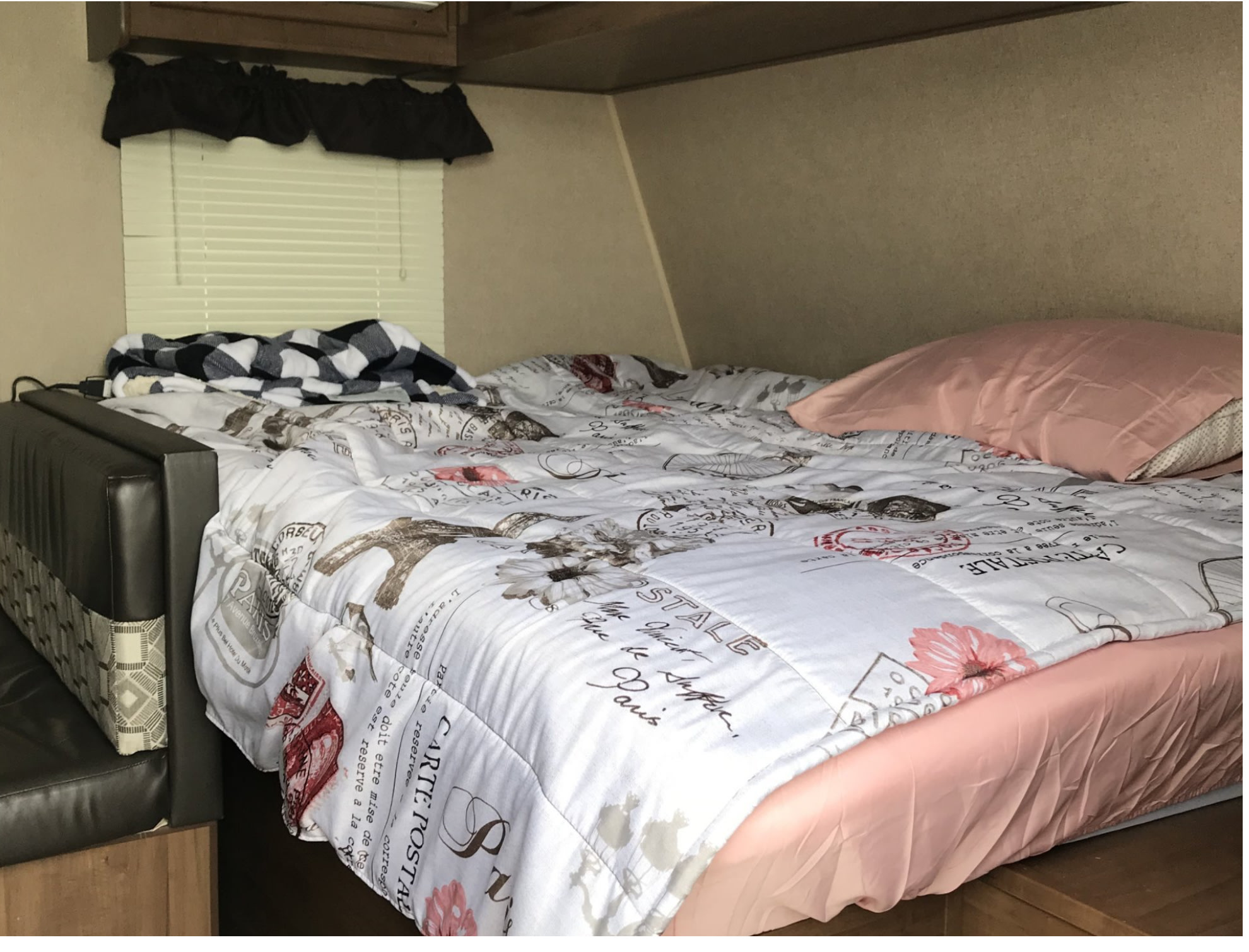 Cozy RV rental bedroom features a bed with Paris-themed comforter, pink pillow, and an adjacent bench.. Aspen Trail Aspen Trail Trailer 2017