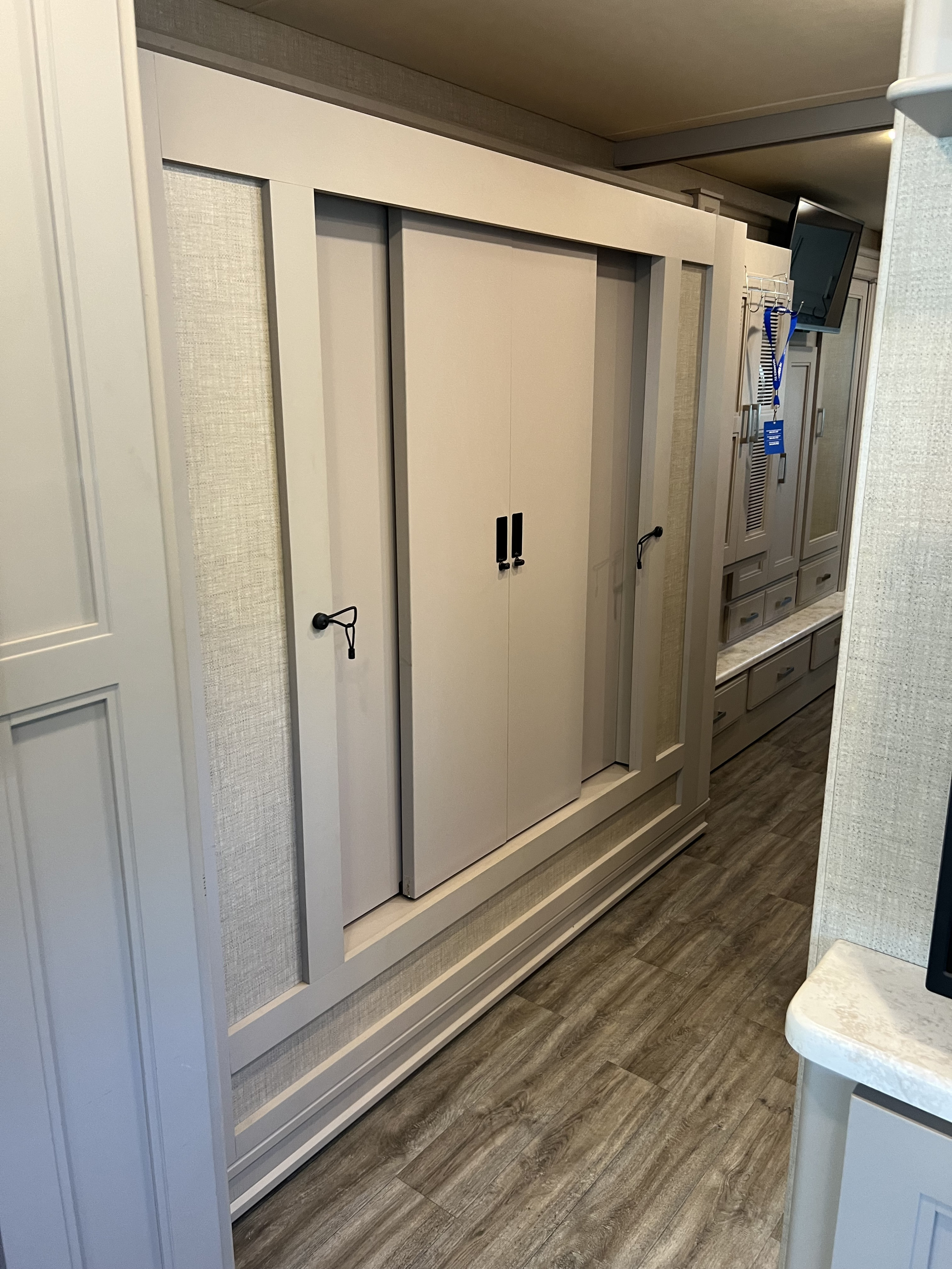 Efficient RV rental interior: A narrow hallway with light-toned sliding storage doors and built-in cabinetry on wood-look floors.. Thor Miramar 2023