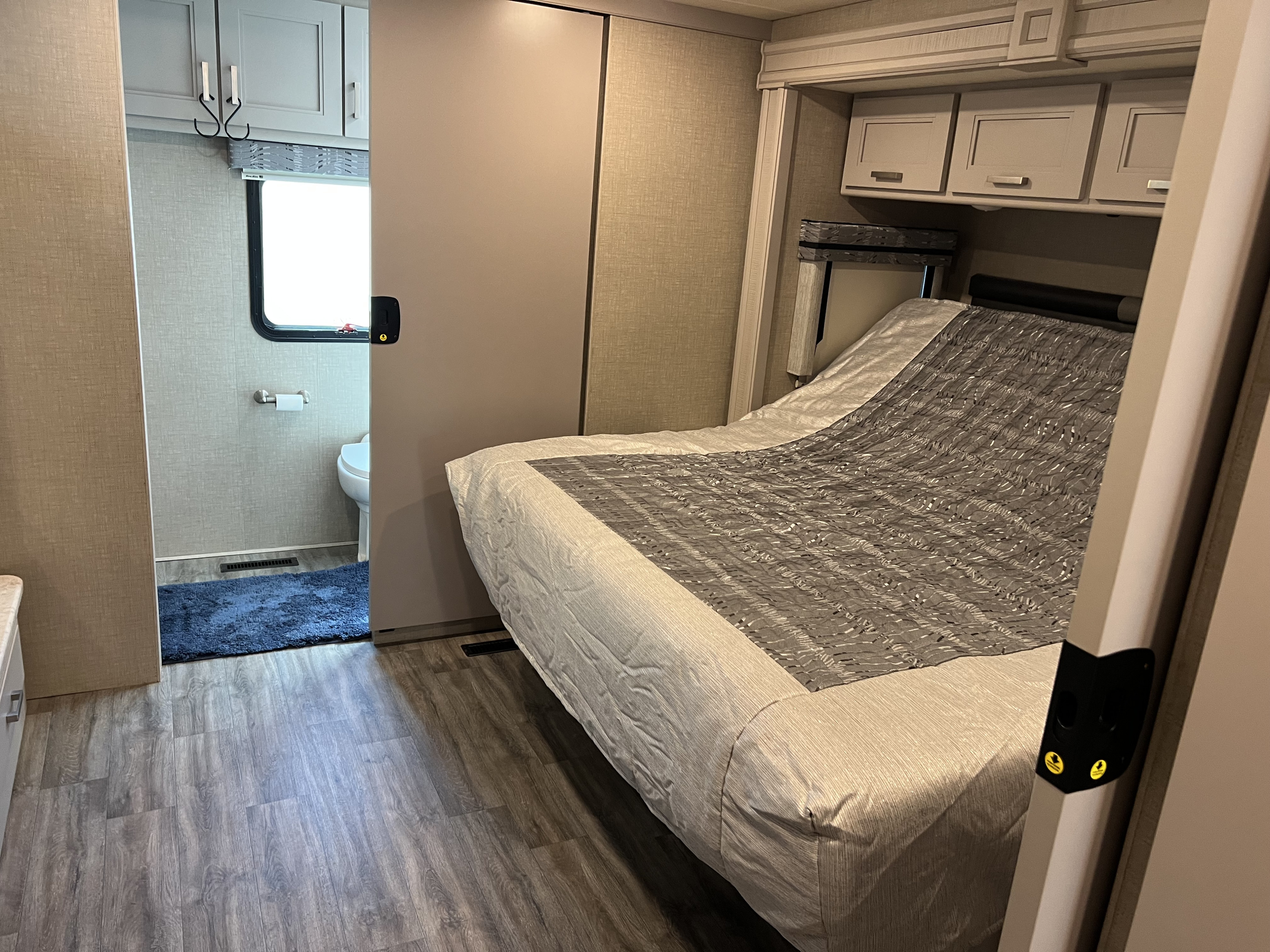RV rental: Interior view of an RV bedroom with a bed and overhead storage, plus an open sliding door to a bathroom.. Thor Miramar 2023