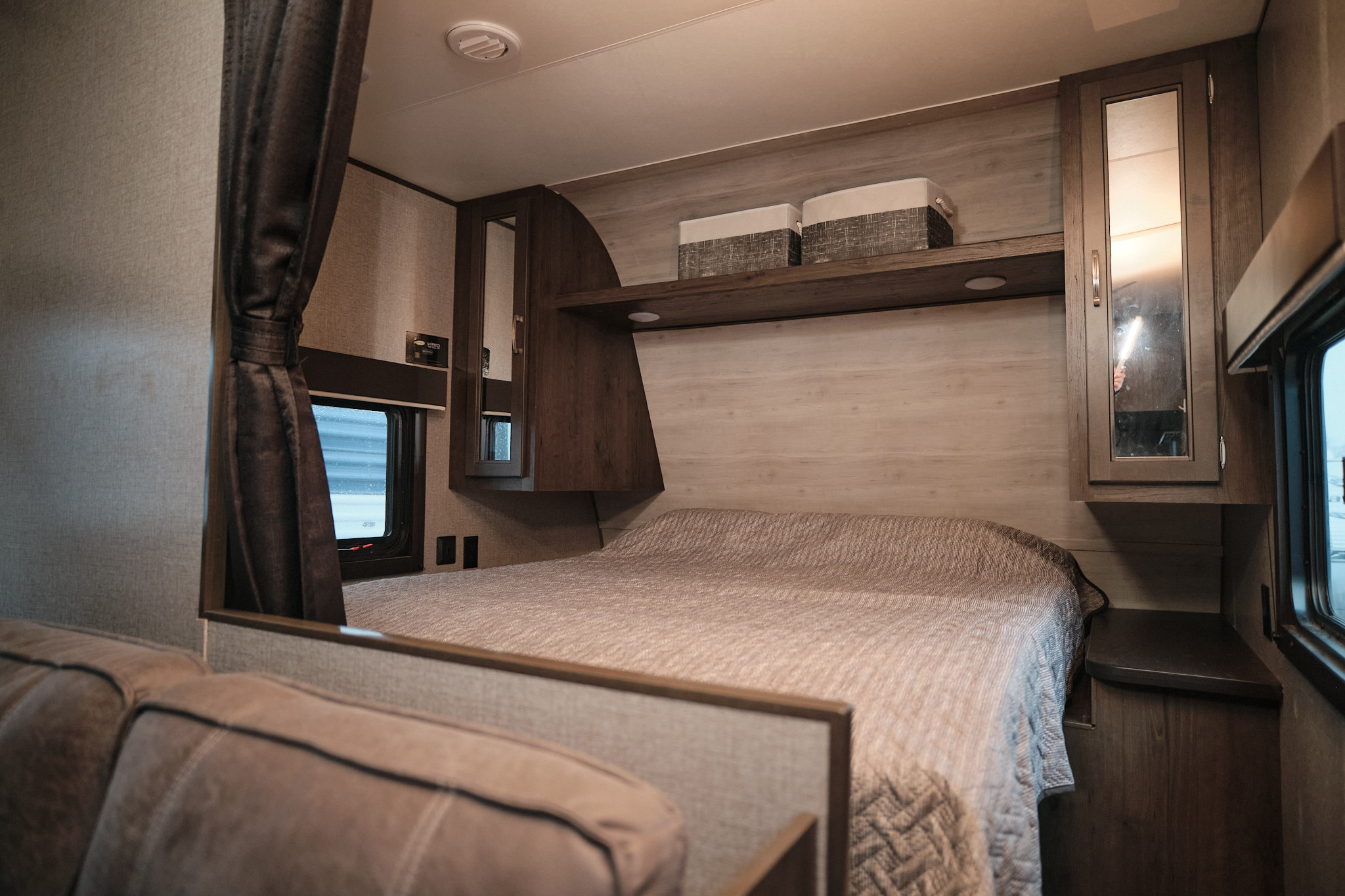 Cozy RV rental interior showing a comfortable bedroom with bed, storage, mirrored cabinet, and window. Ideal for travel.. Jayco Jay Flight 2021