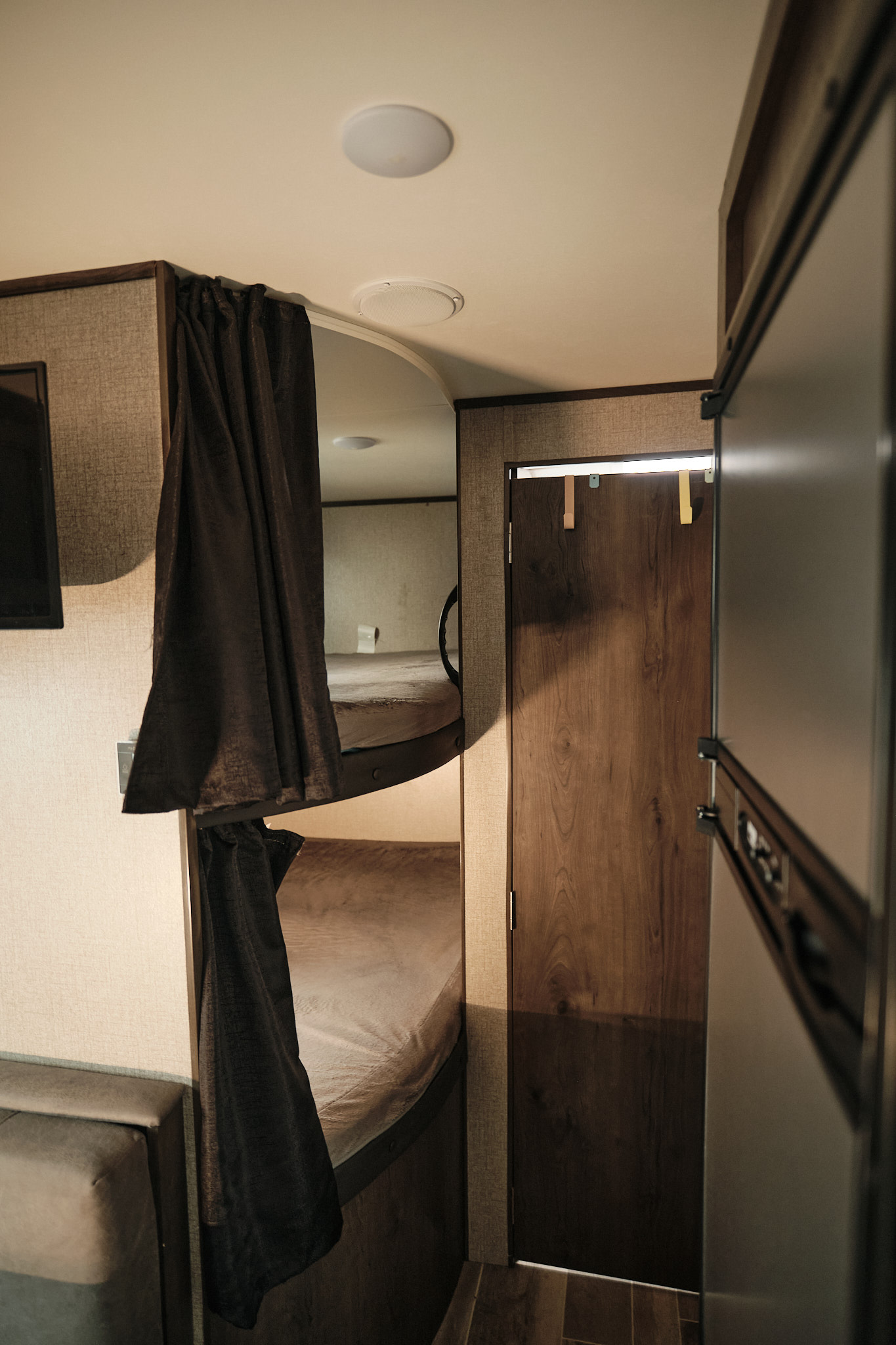 RV rental interior view showing cozy bunk beds with privacy curtains, a wooden door, and compact living space.. Jayco Jay Flight 2021