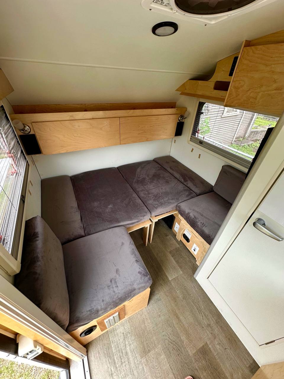 Cozy RV rental interior features a versatile convertible bed, ample overhead storage, and wood-look flooring.. nuCamp T@B 2022
