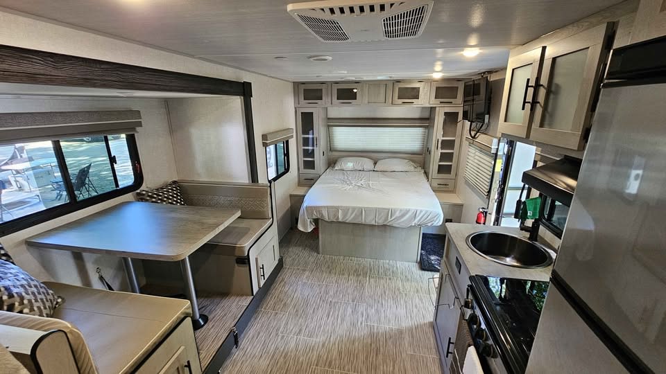 RV rental interior: A bright, modern space with a bedroom, dining booth, and compact kitchen visible from the entrance.. Forest River Ibex 2022